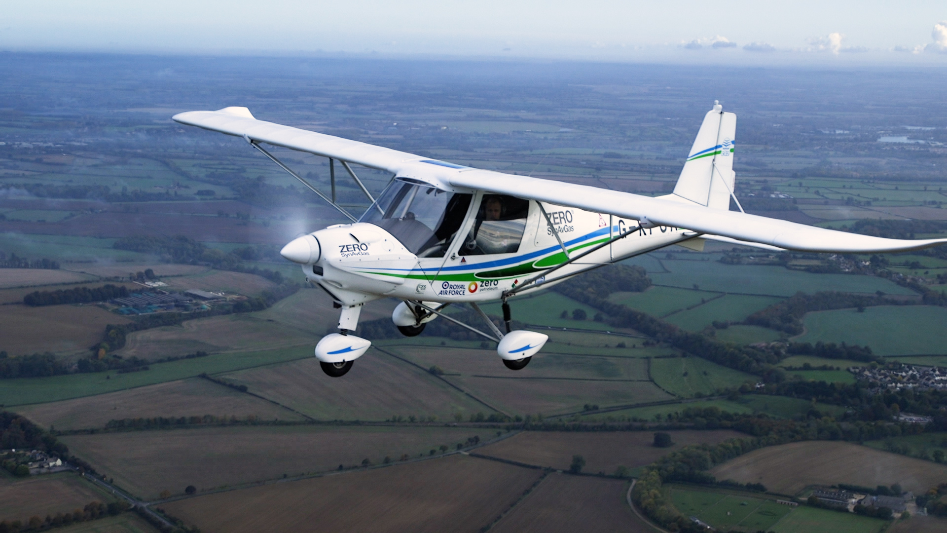 Image shows a microlight aircraft in flight over fields.