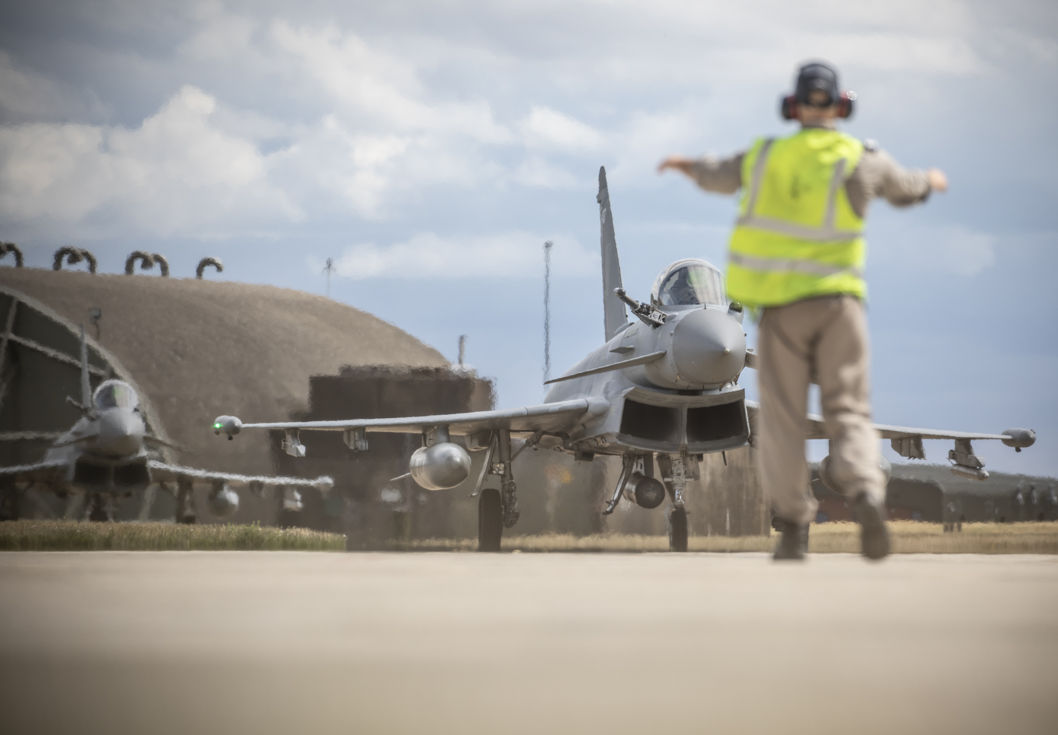 Image shows RAF aviator guiding Typhoons on the airfield.
