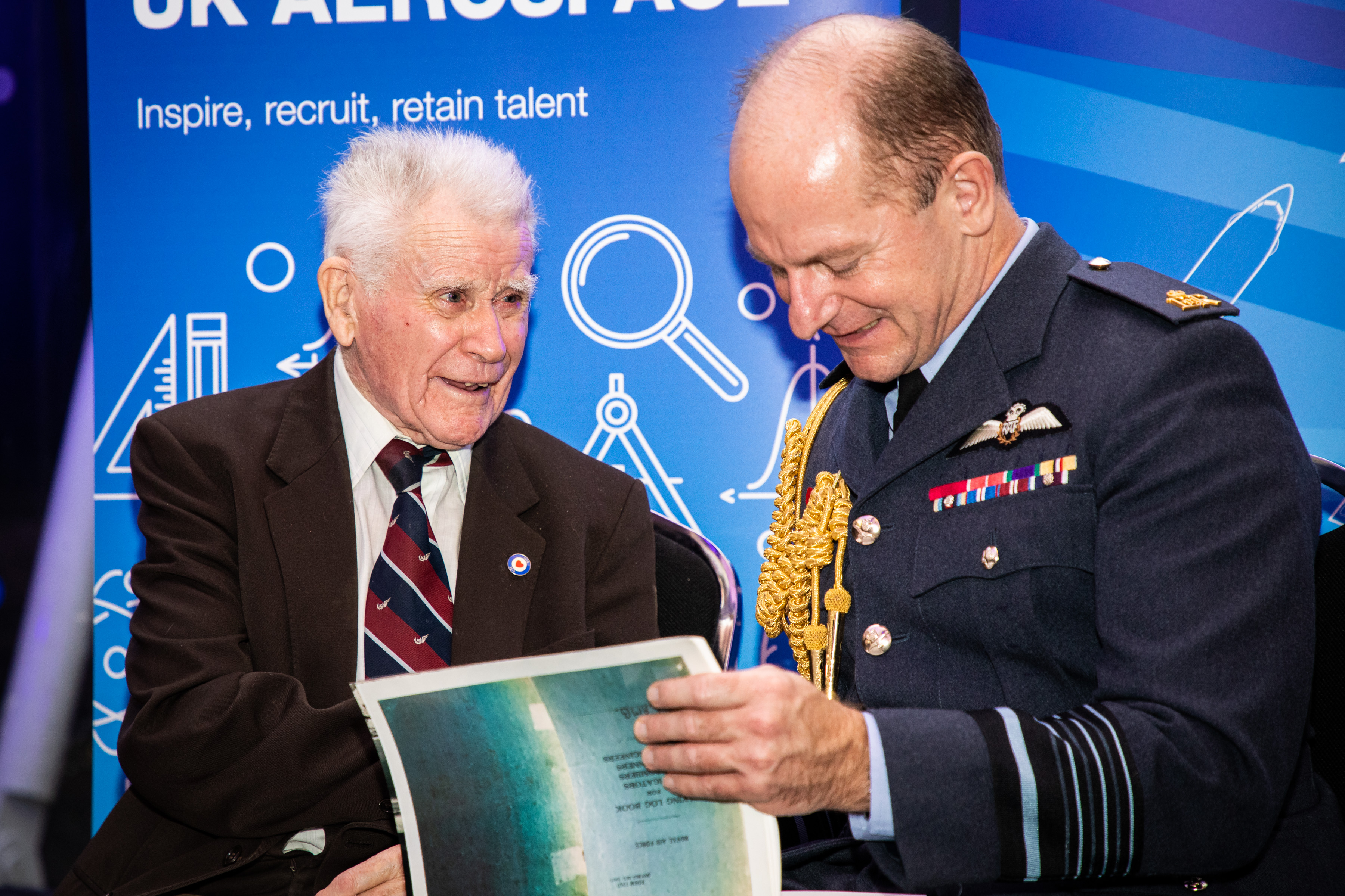 Air-Vice Marshal Sir Mike Wigston looks through booklet with veteran.