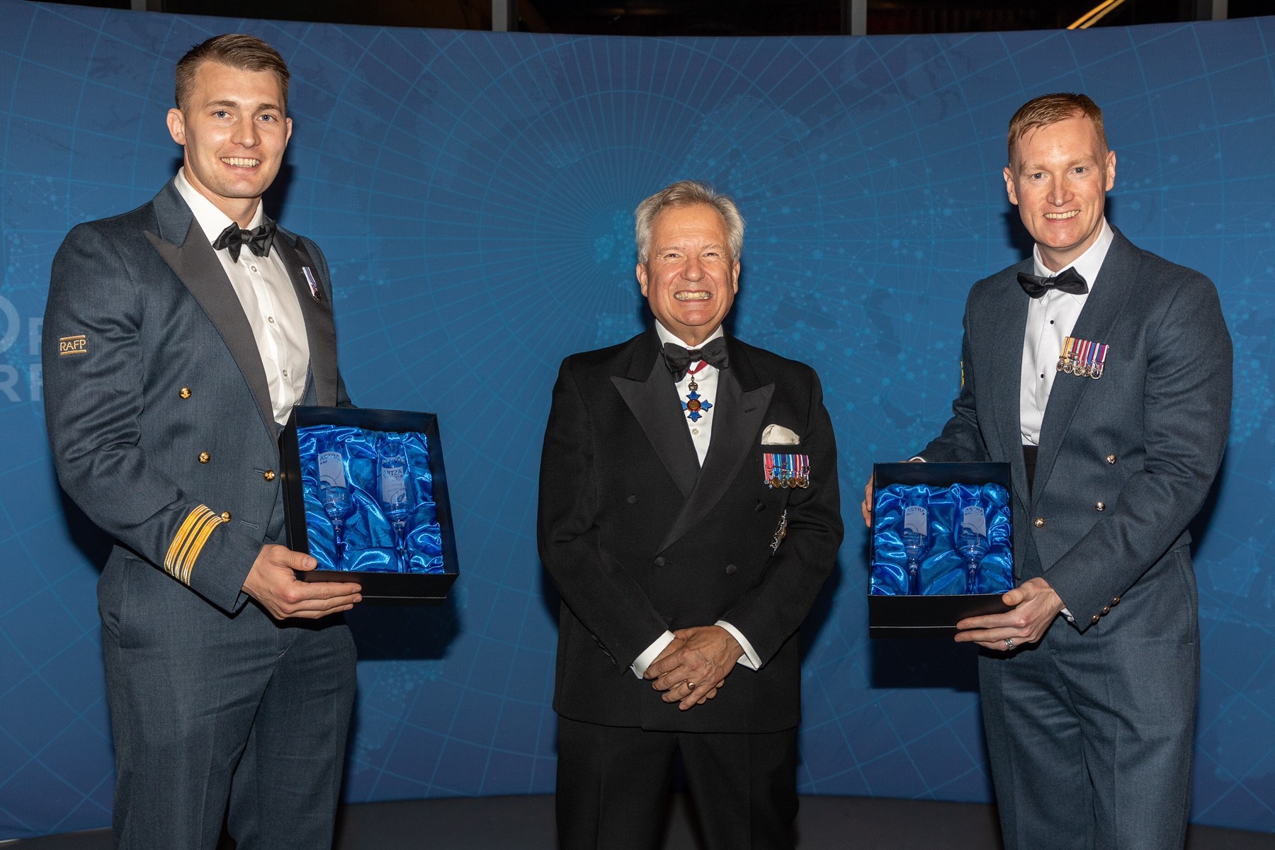 Image shows RAF aviators holding awards for picture at awards ceremony.
