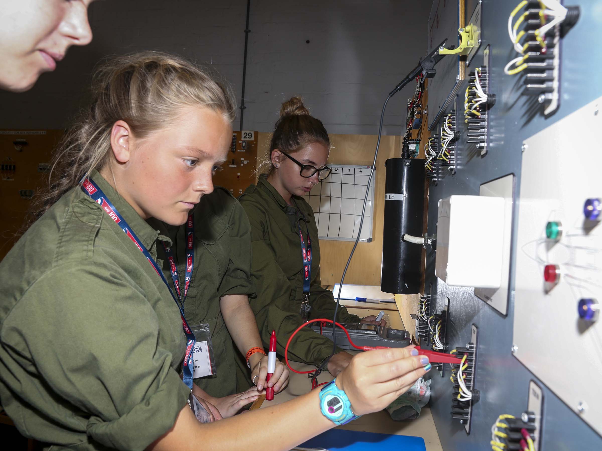 Image shows RAF Technicians wiring cables in a wall over a desk.