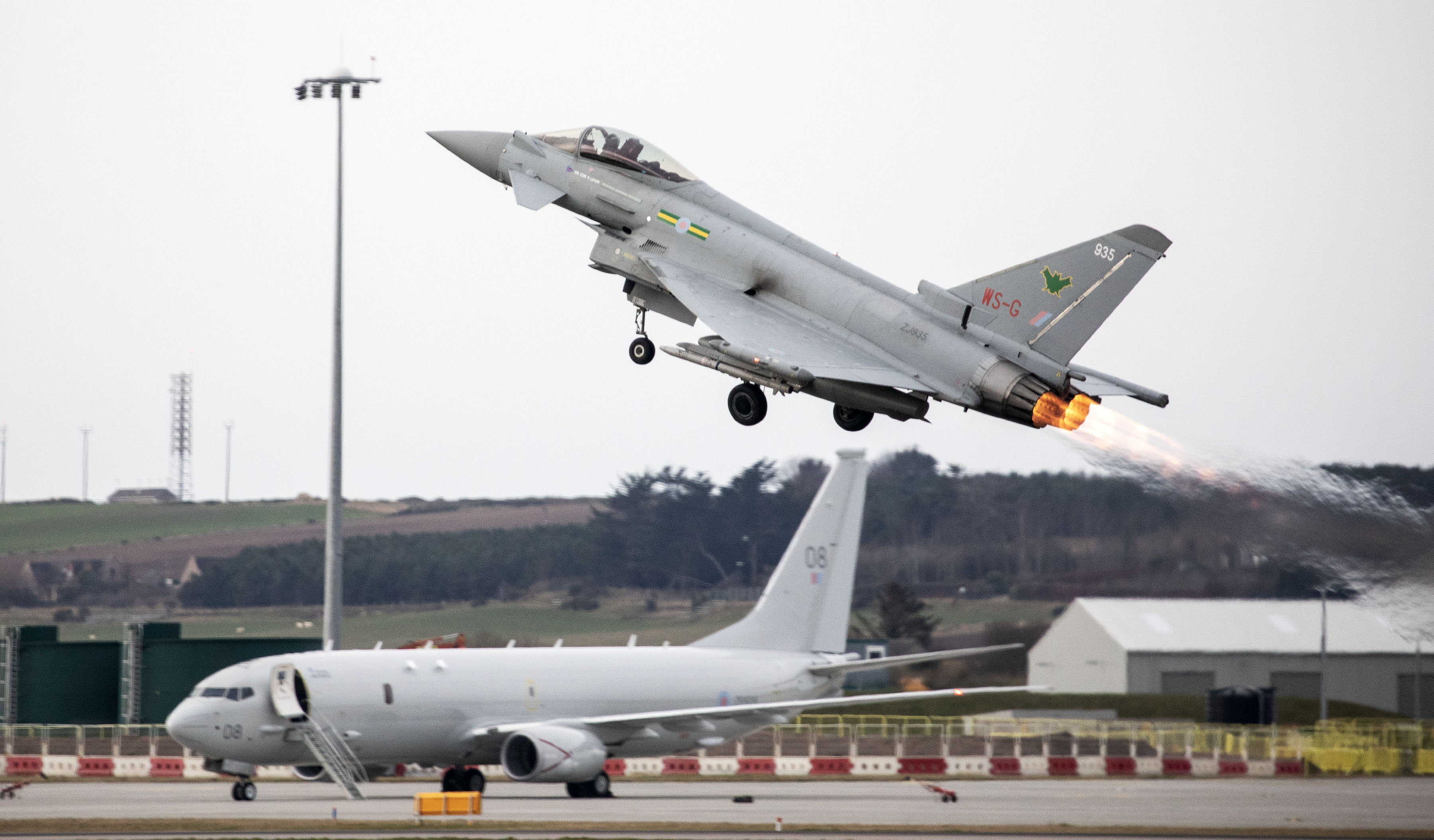 Image shows RAF Voyager on the airfield with a Typhoon taking off over it.