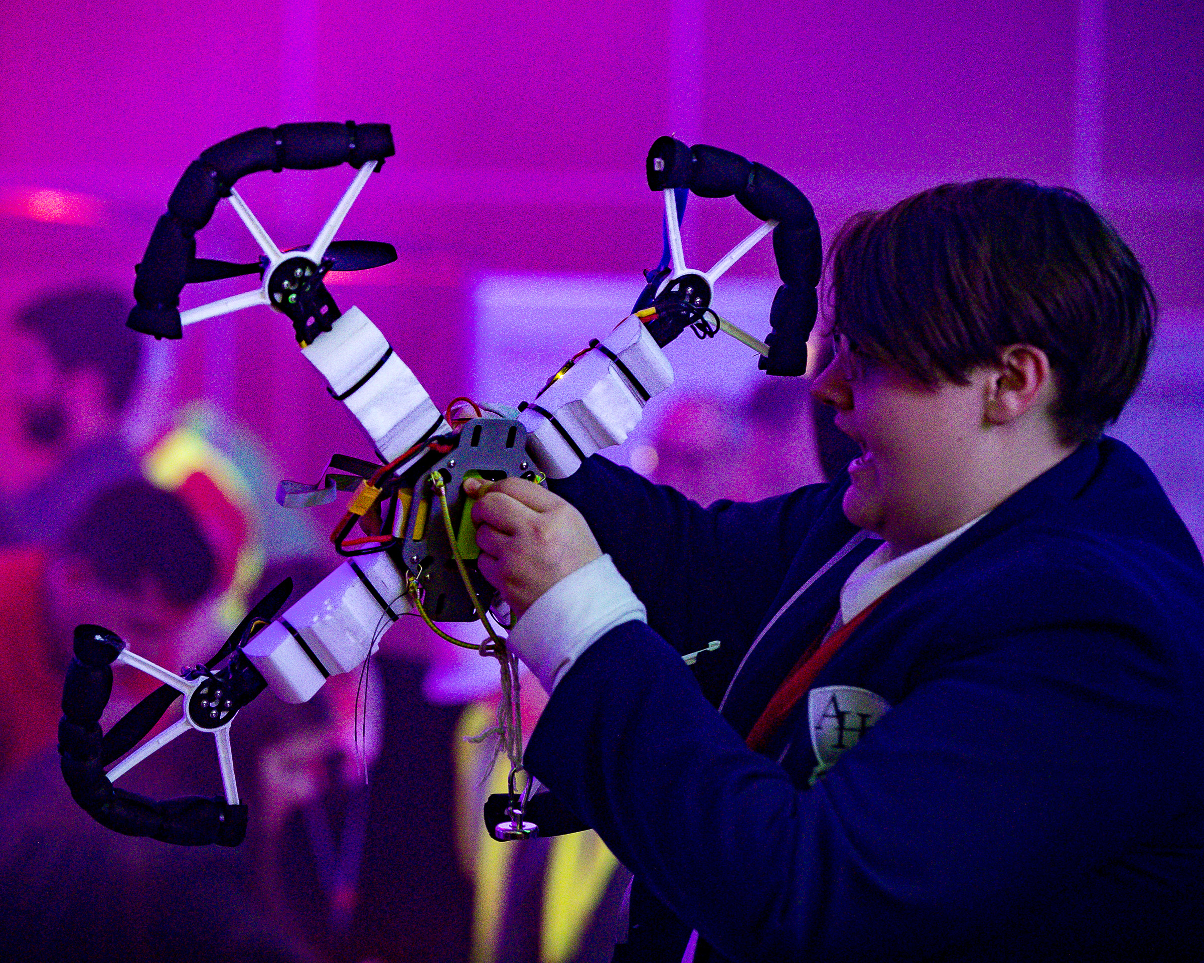 Image shows a school student holding a quadcopter model.