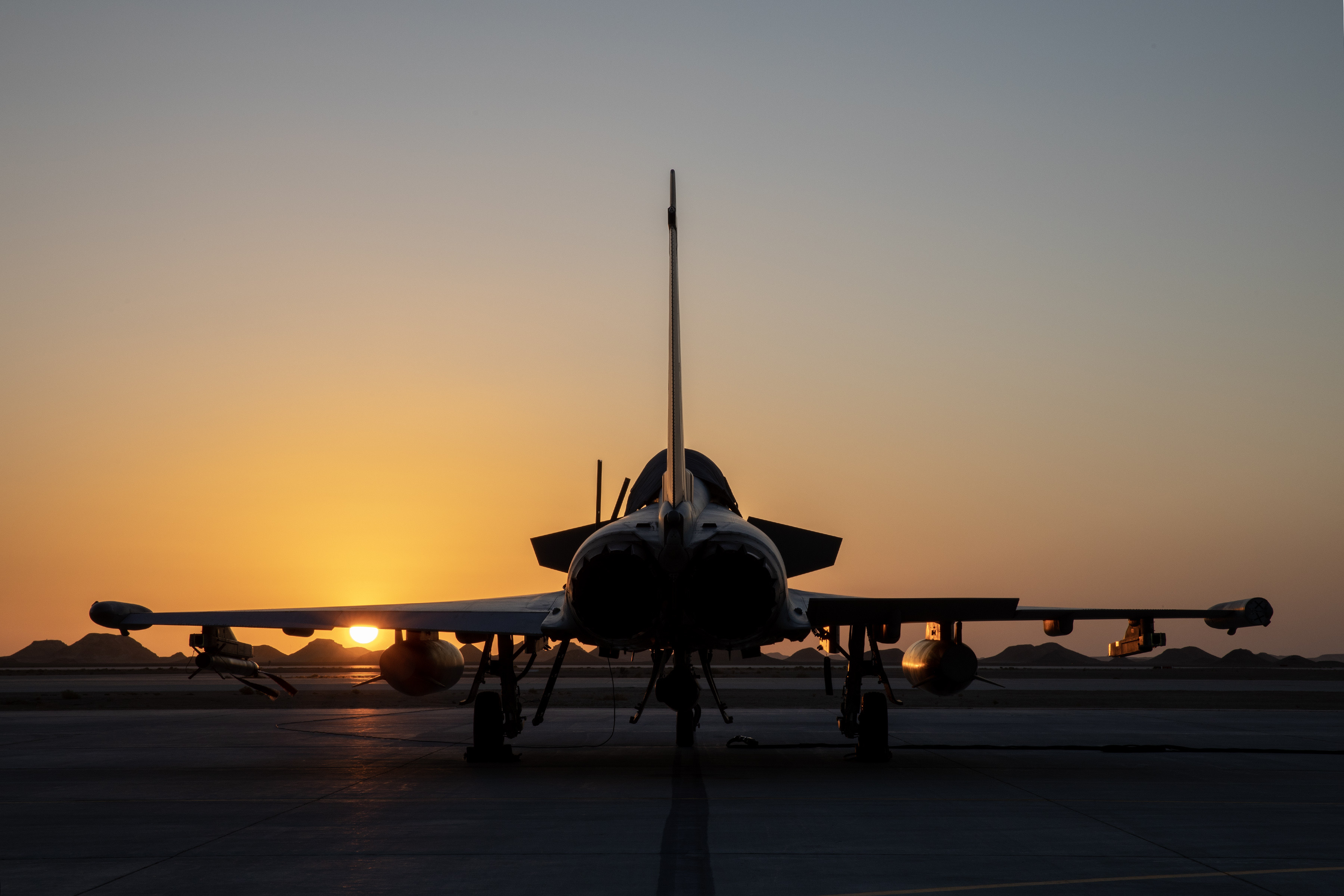 Image shows RAF Typhoons on the airfield under a sunset.