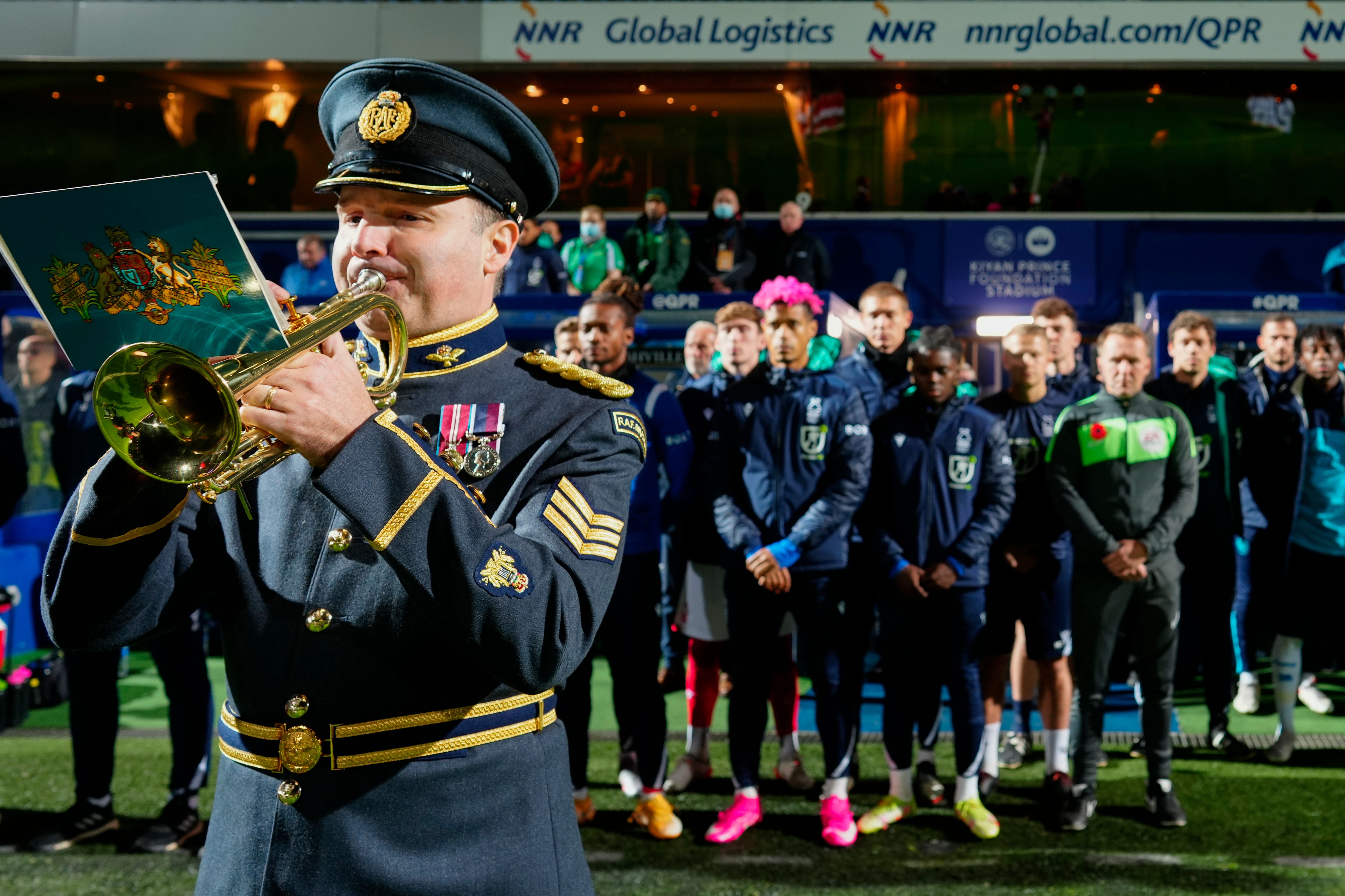 Trumpeter plays the trumpet with football team standing behind.