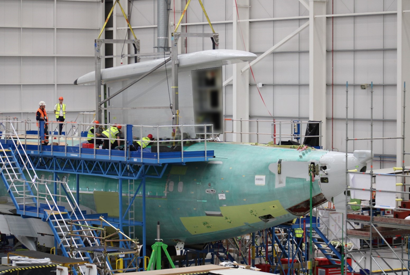 Image shows aircraft parts being assembled inside hangar.