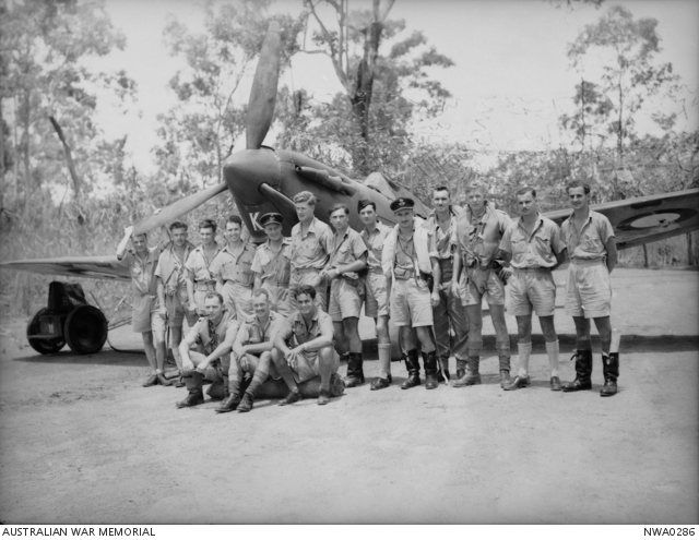 Black and white image of RAF squadron posing by a Spitfire on the airfield.
