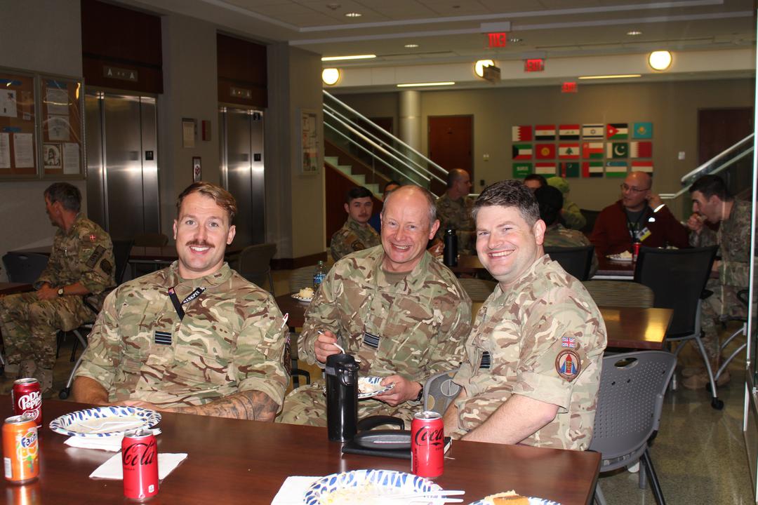 Image shows RAF aviators smiling around a mess table. 