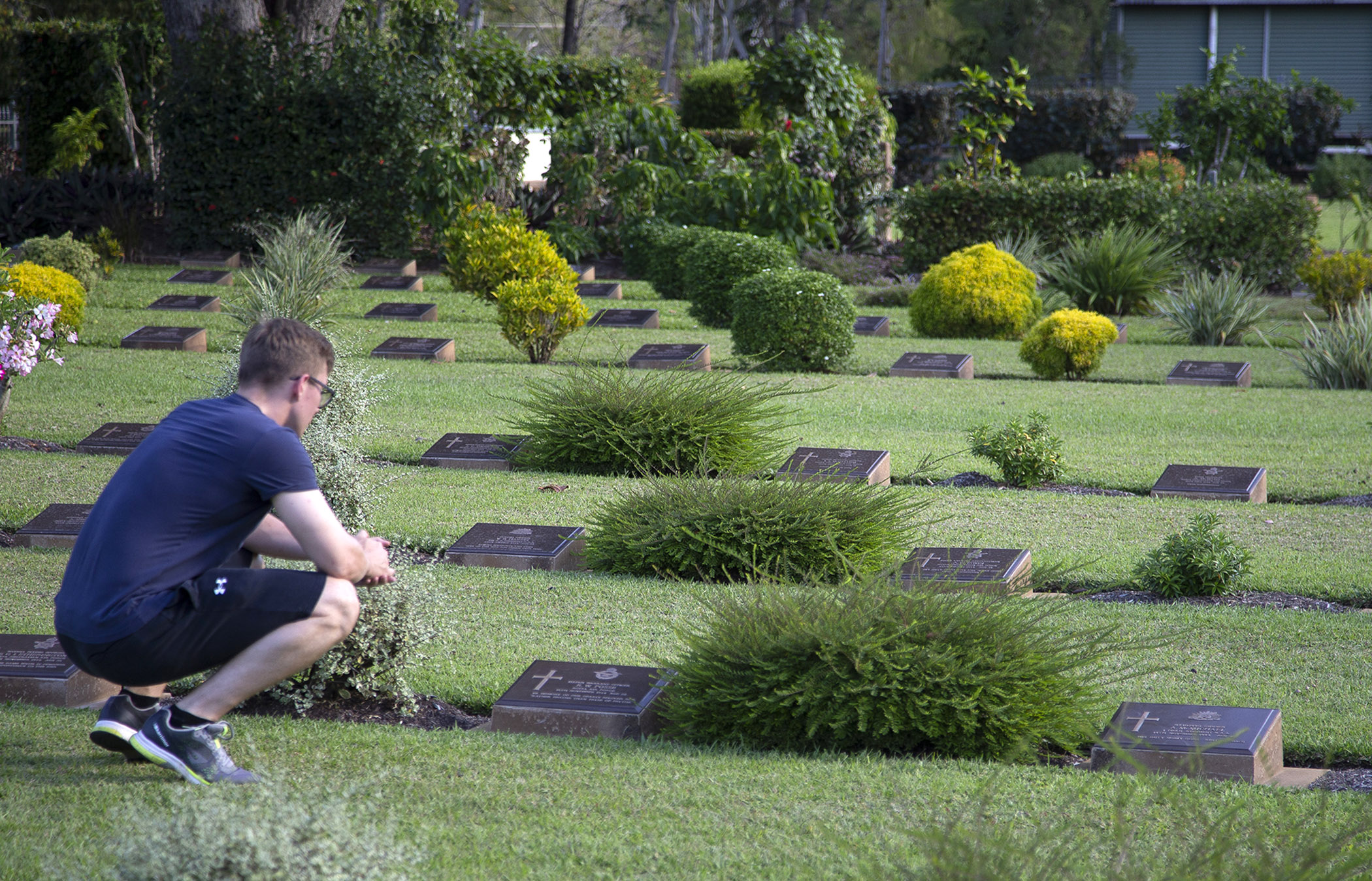 Image shows onlooker crouching by headstones in a cemetery/