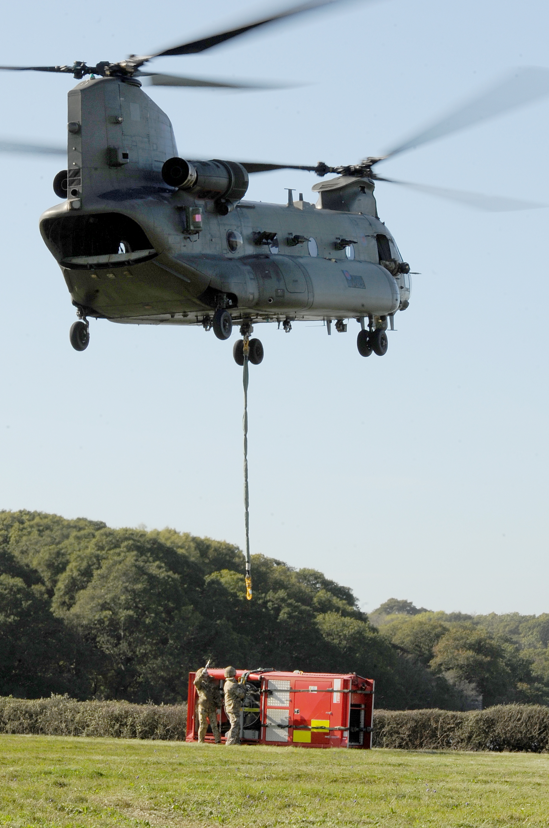 Image shows Chinook dropping under slung cargo to the ground.