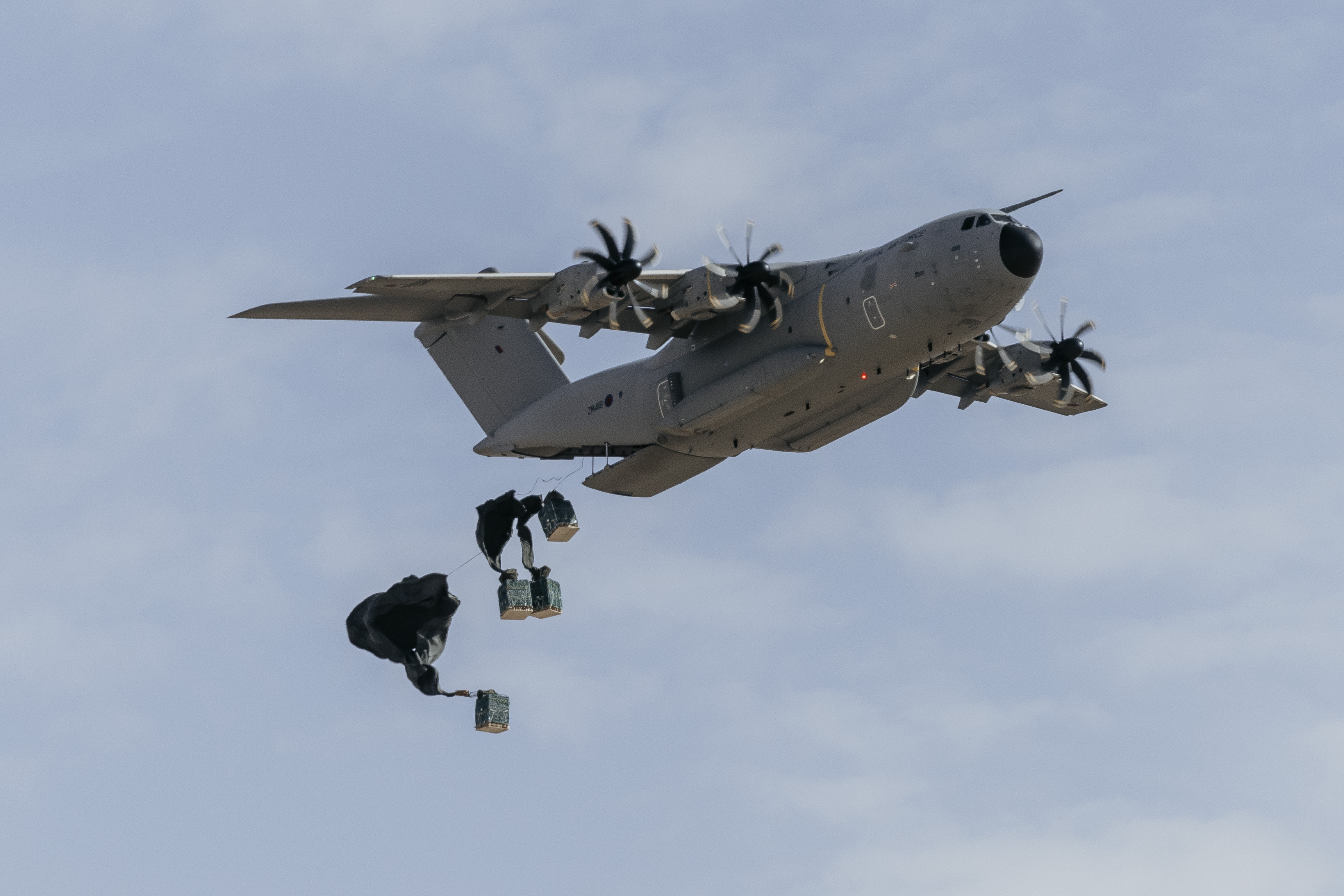 Image shows RAF Altas dropping cargo from loading bay, as they deploy parachutes.