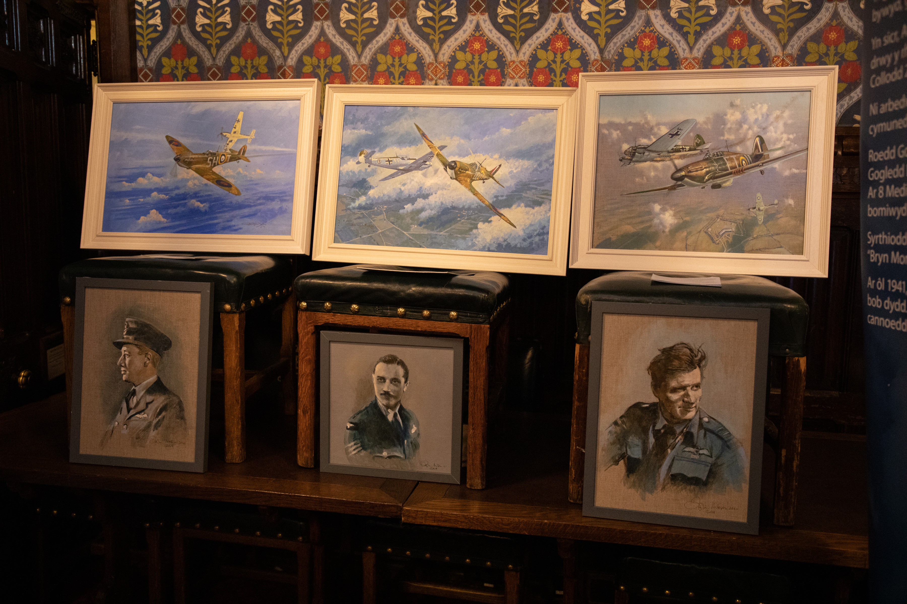 Image shows six portraits of RAF aviators and Spitfires on display in exhibit.