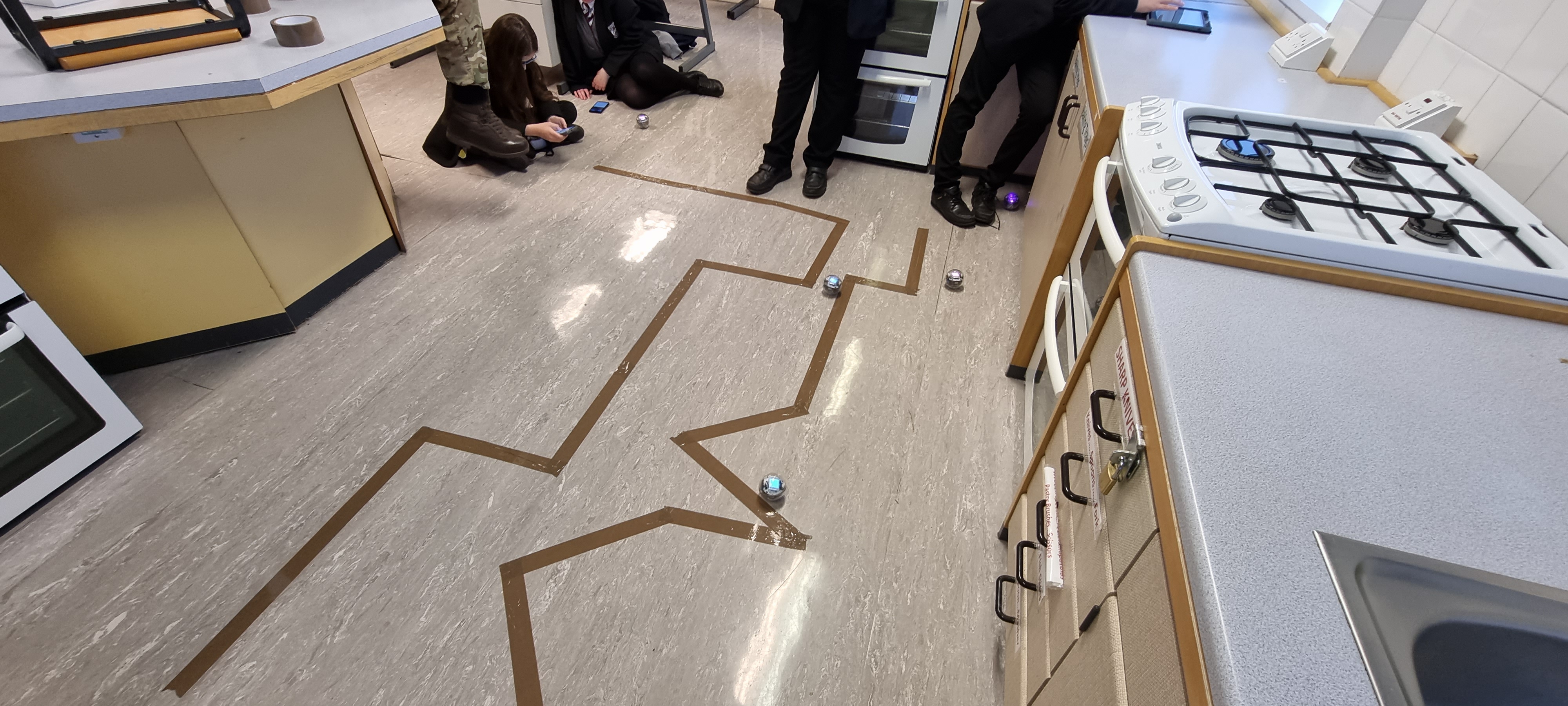 Students push sphero balls along course laid out on the ground.
