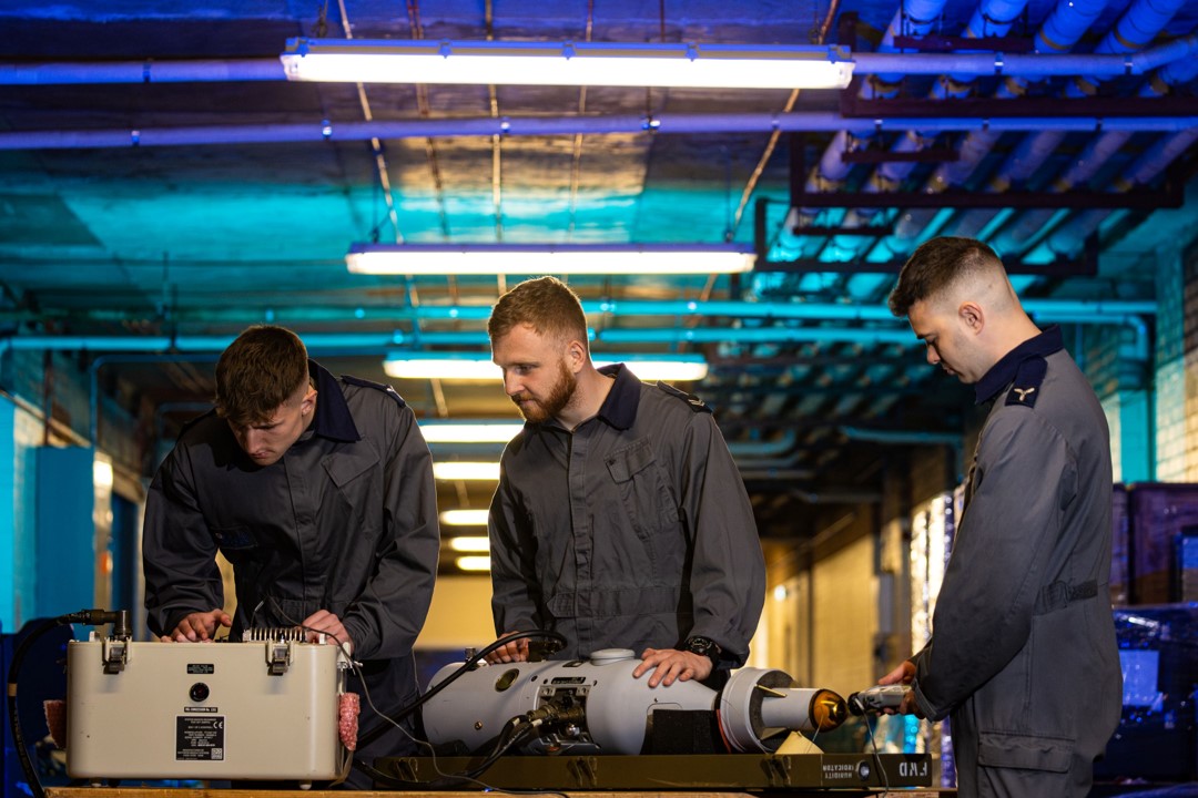 3 RAF Armourers working on equipment in a blue lit room