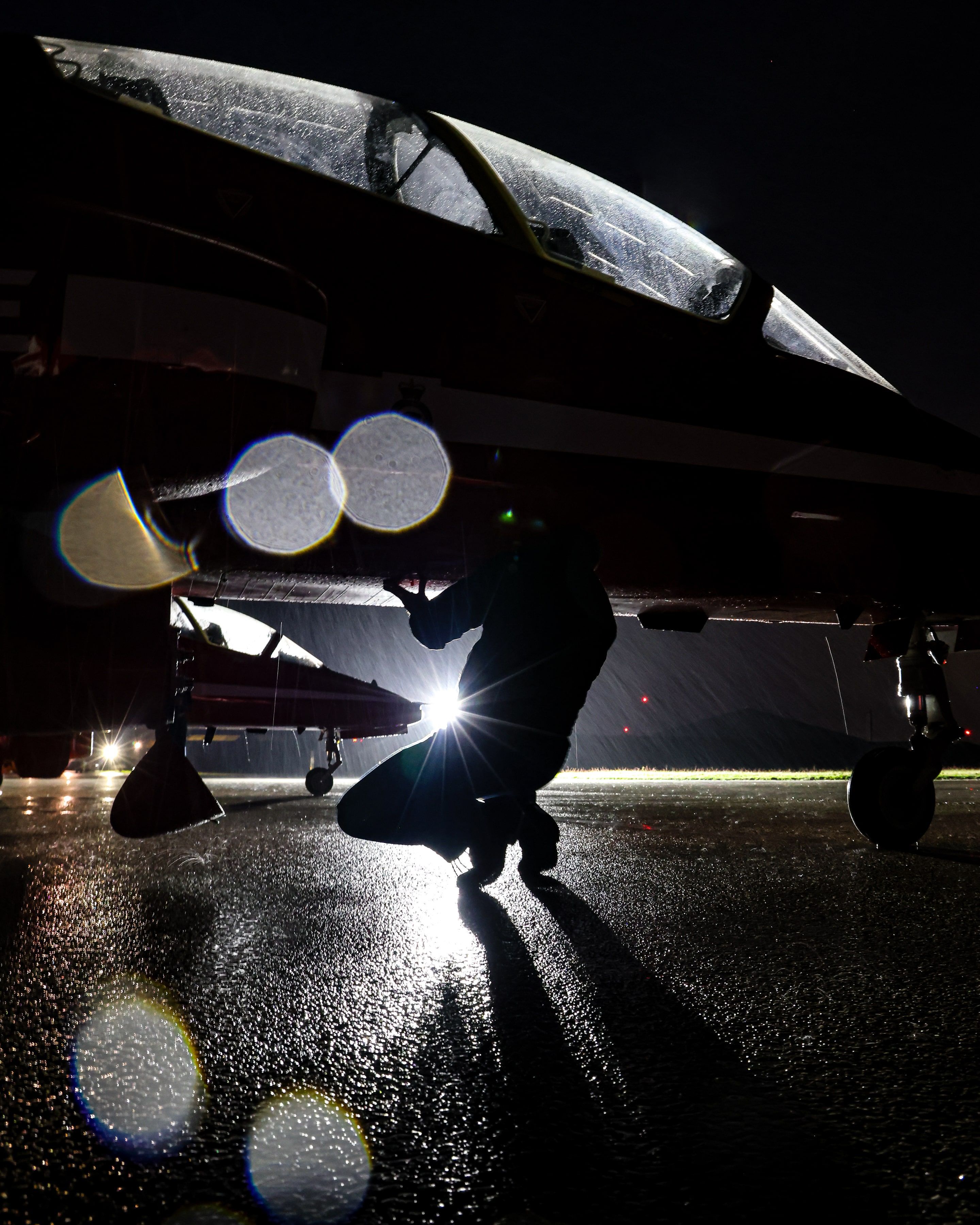 Engineer at night under the cockpit of an aircraft in the rain