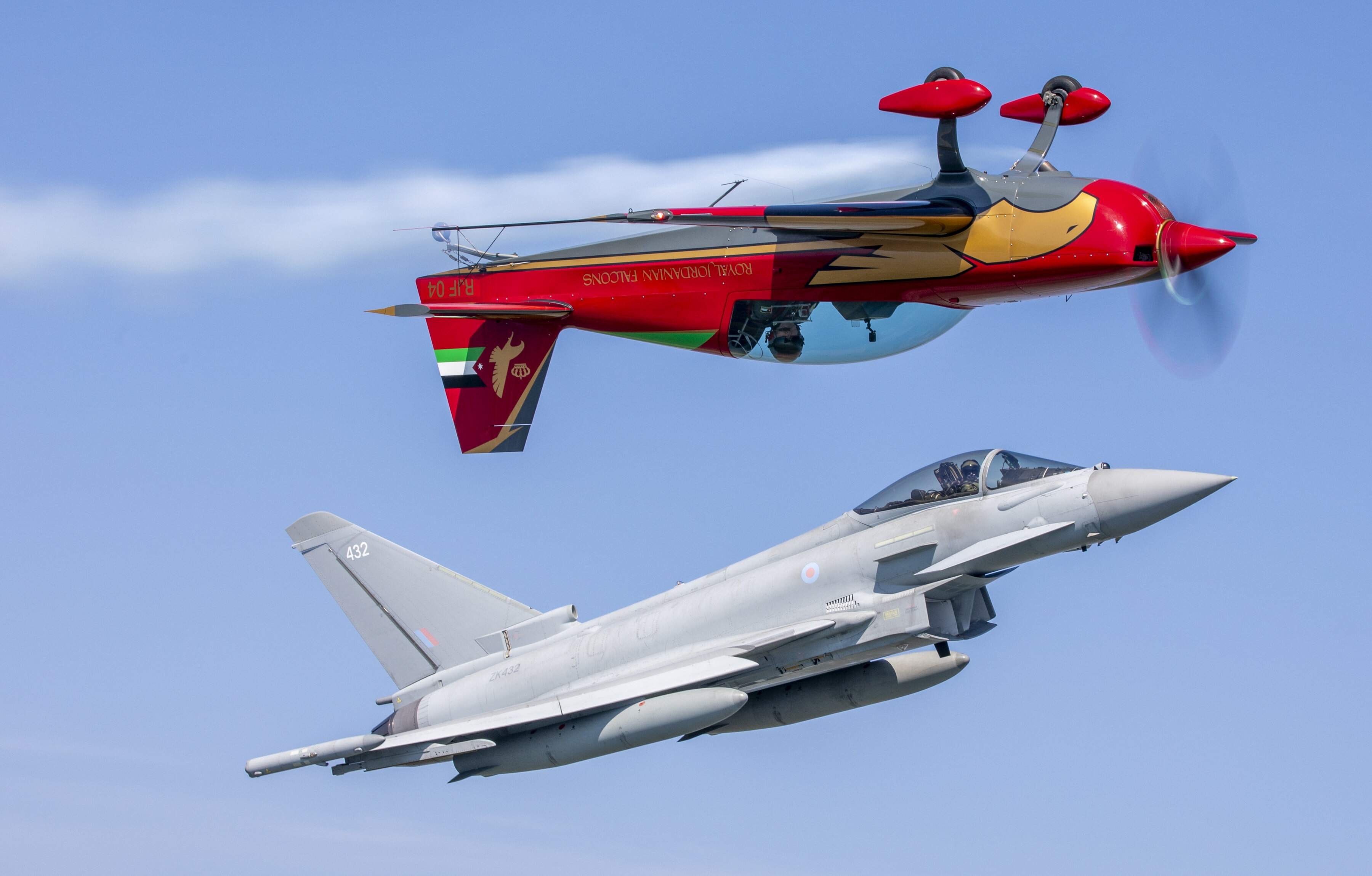RAF Typhoon flying with an upside down Royal Jordanian Forces propeller aircraft flying above