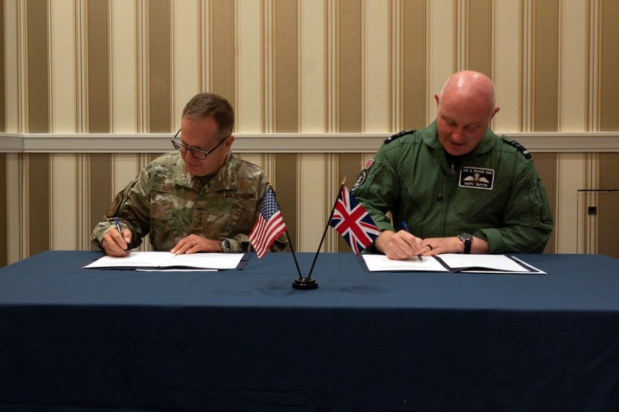 Military personnel sat at table signing document