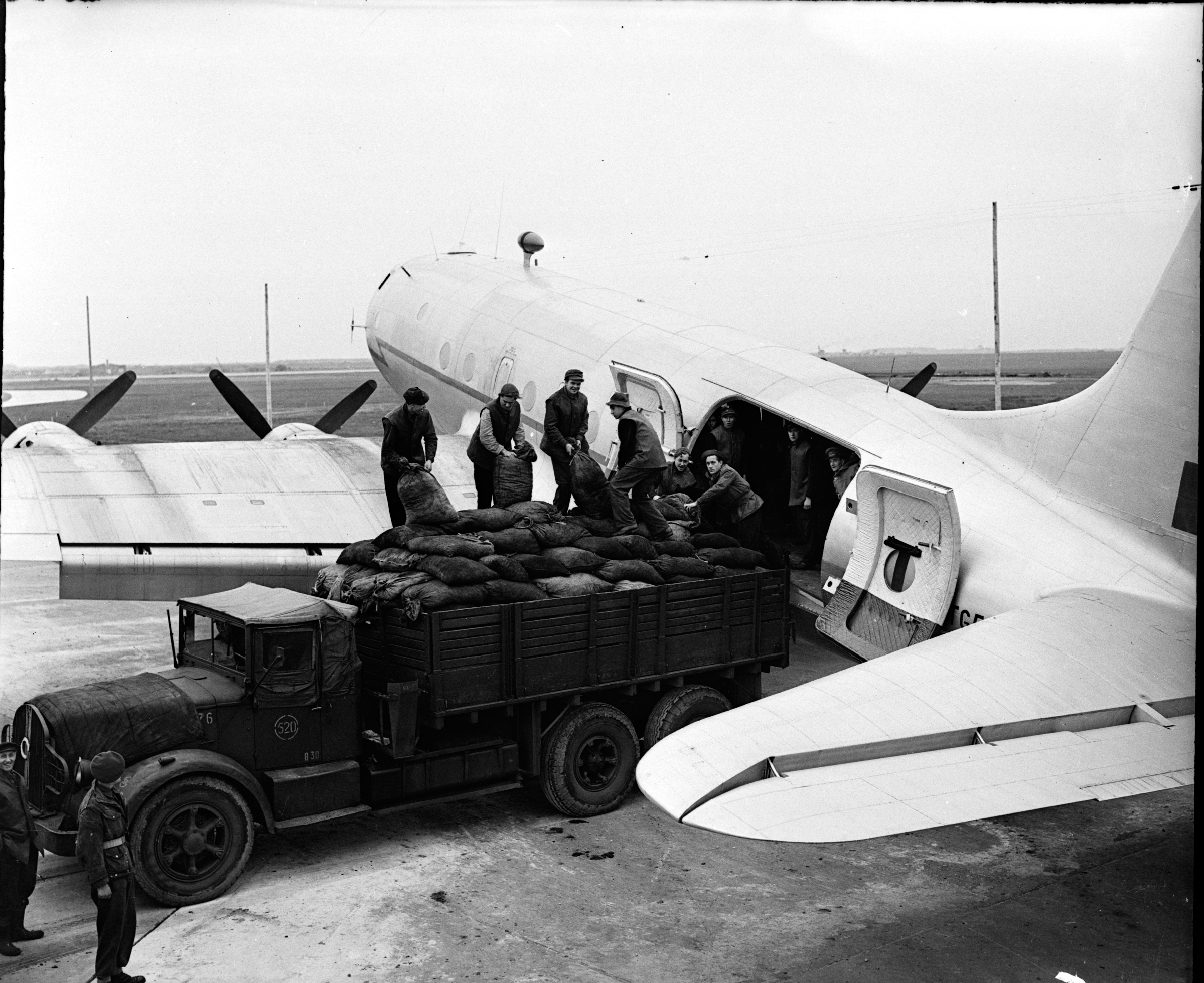 Black and white image shows an RAF aircraft being loaded/unloaded.