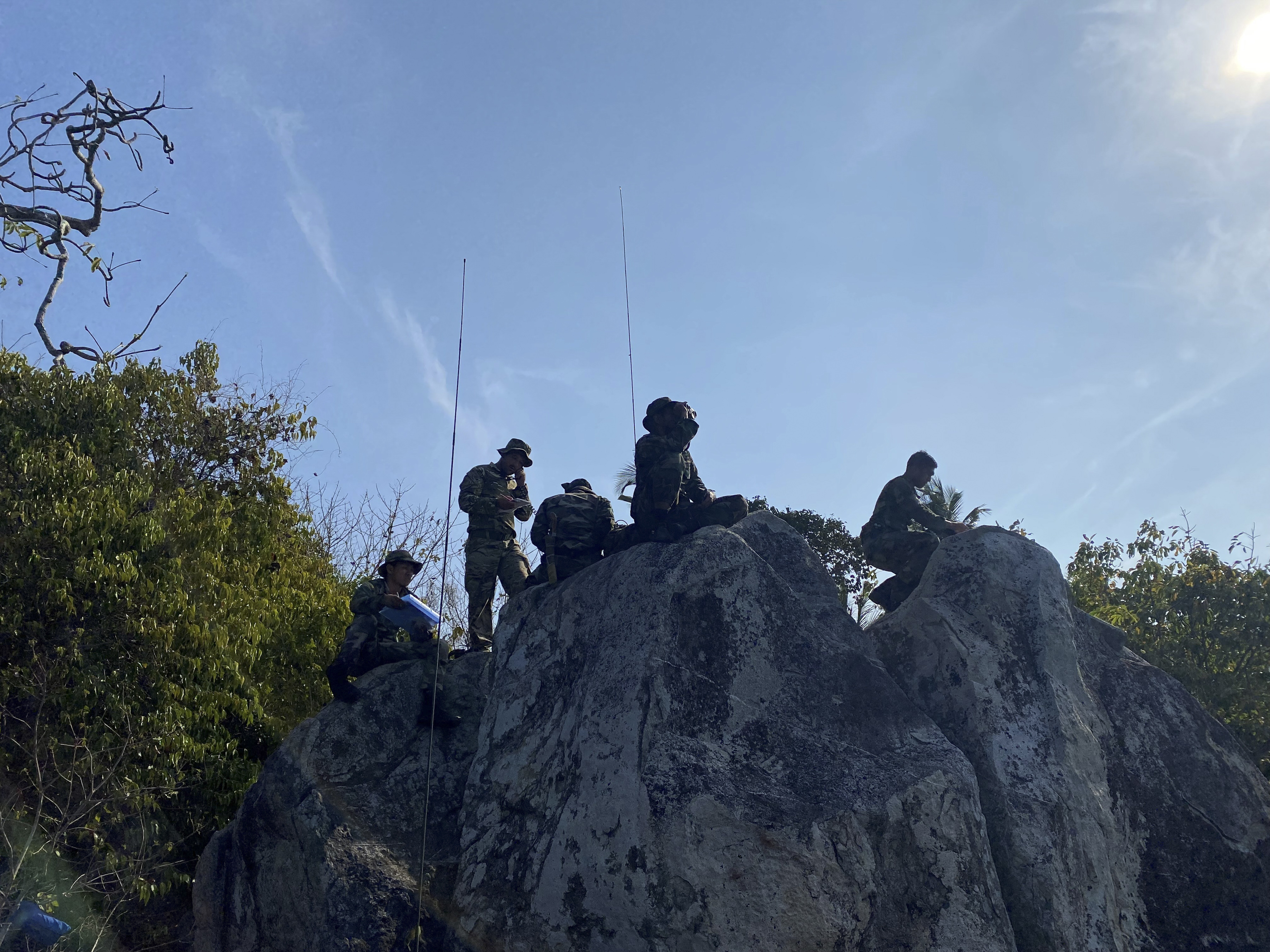 military personnel atop a rocky outcrop as an observation post