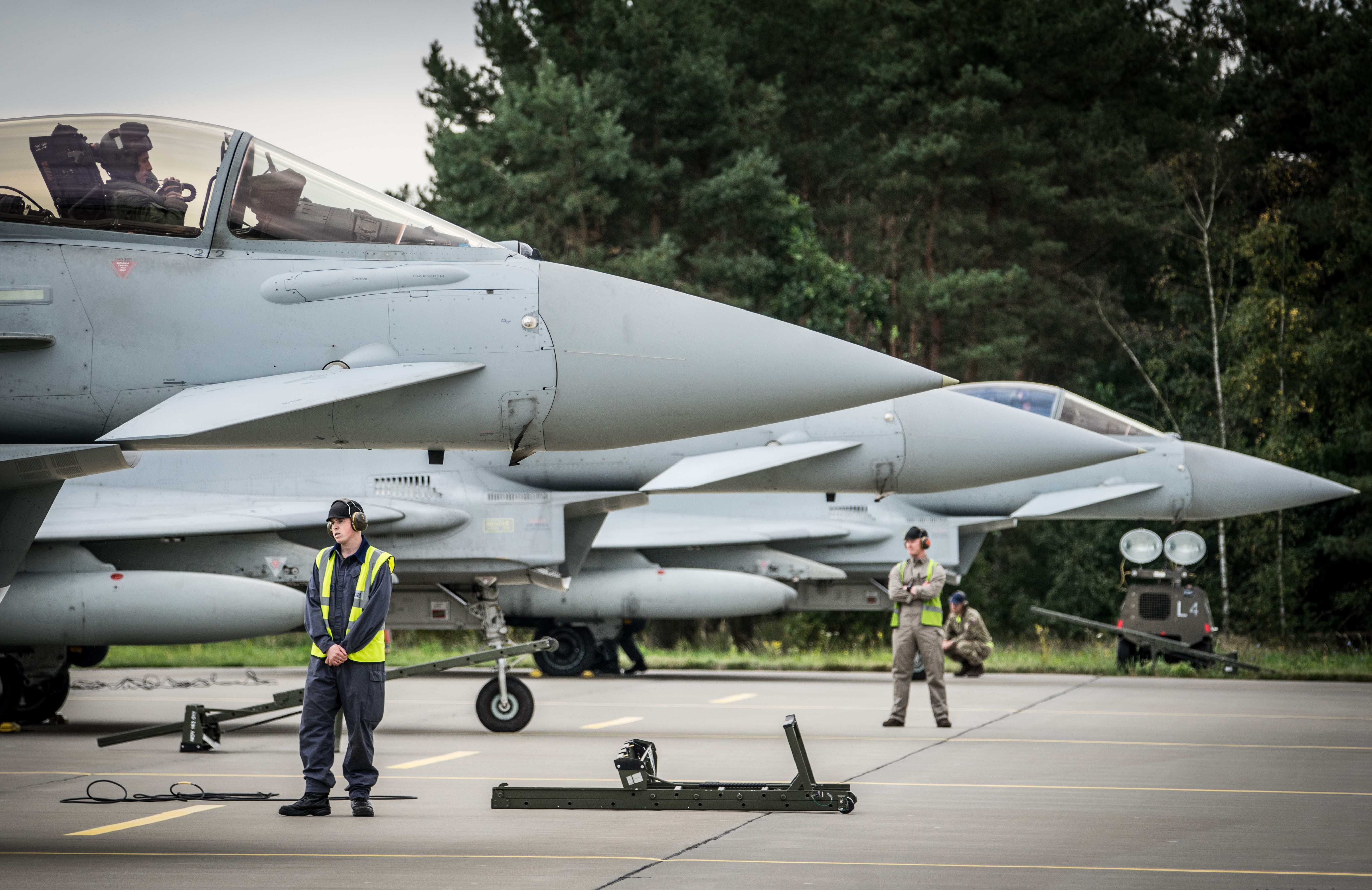 The nose of 2 Typhoons seen on the runway, with engineers positioned beside them. 