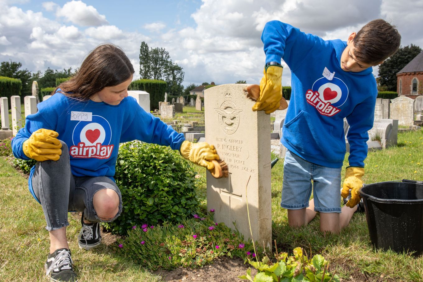 Young people cleaning Flying Officer Ingelby's war grave.