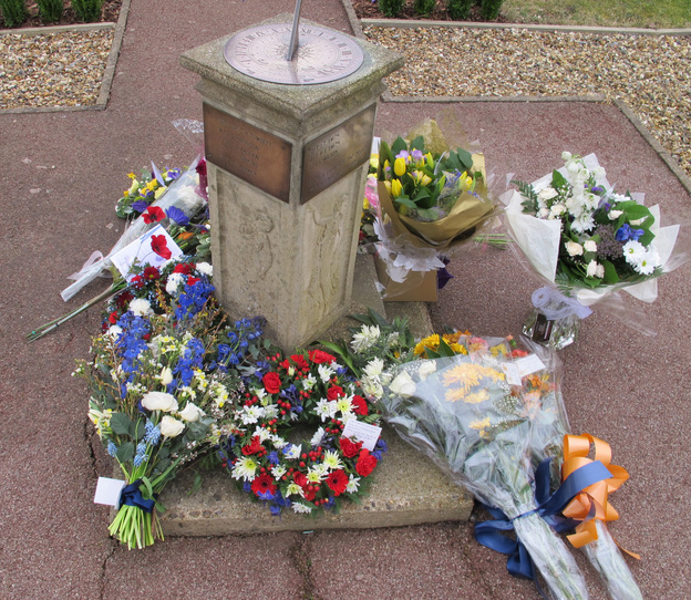 Sundial memorial surrounded by flowers.