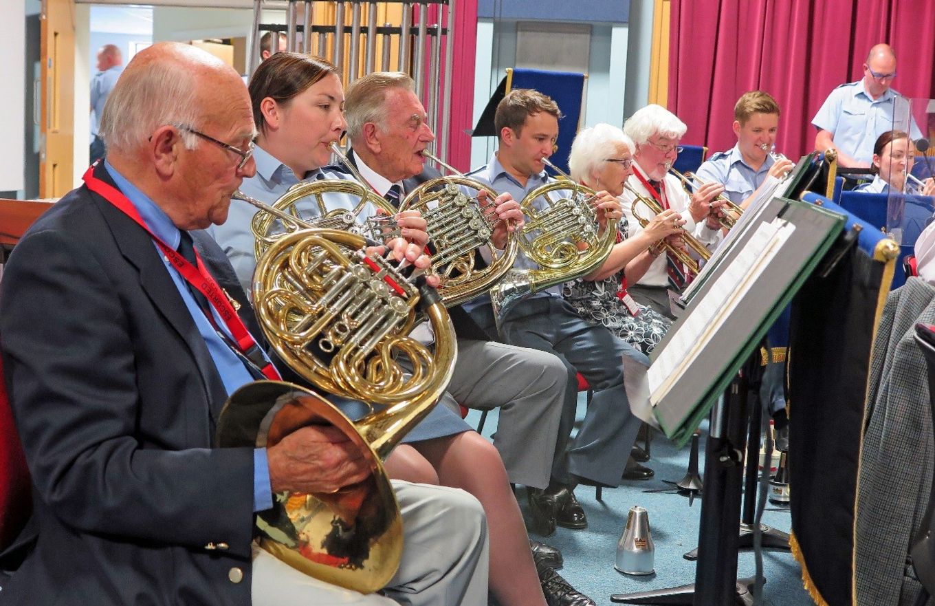 Uniformed and non-uniformed french horn players enjoy making music together.