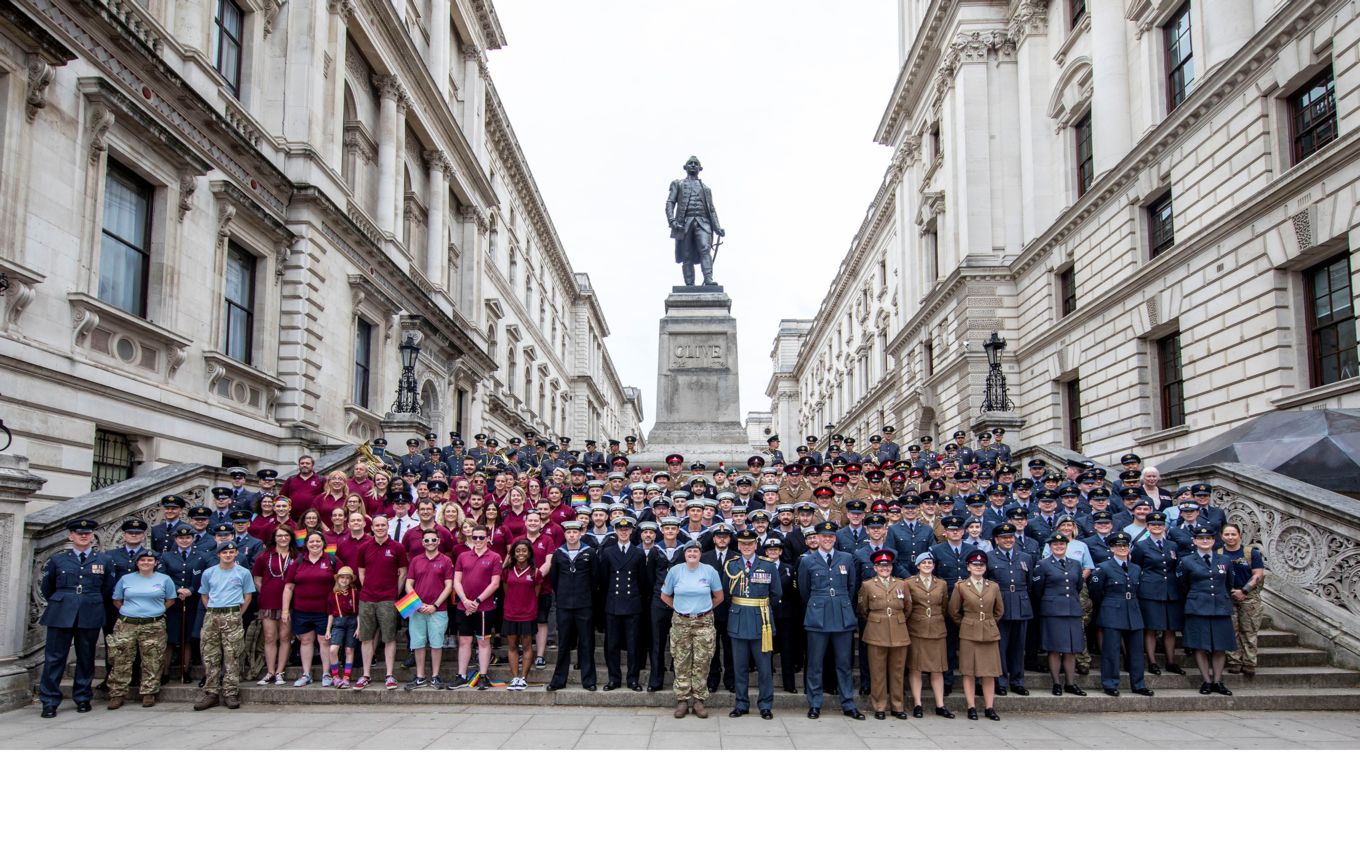Uniformed men and women from the Navy, Army and RAF pose for a photo.