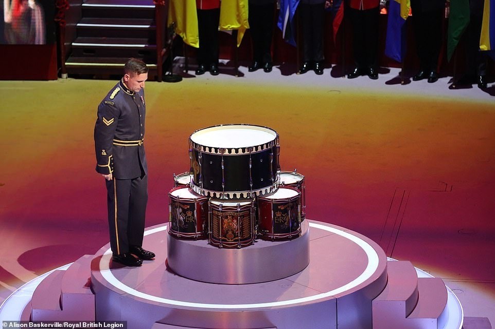 A musician bows their head in front of a drum altar.