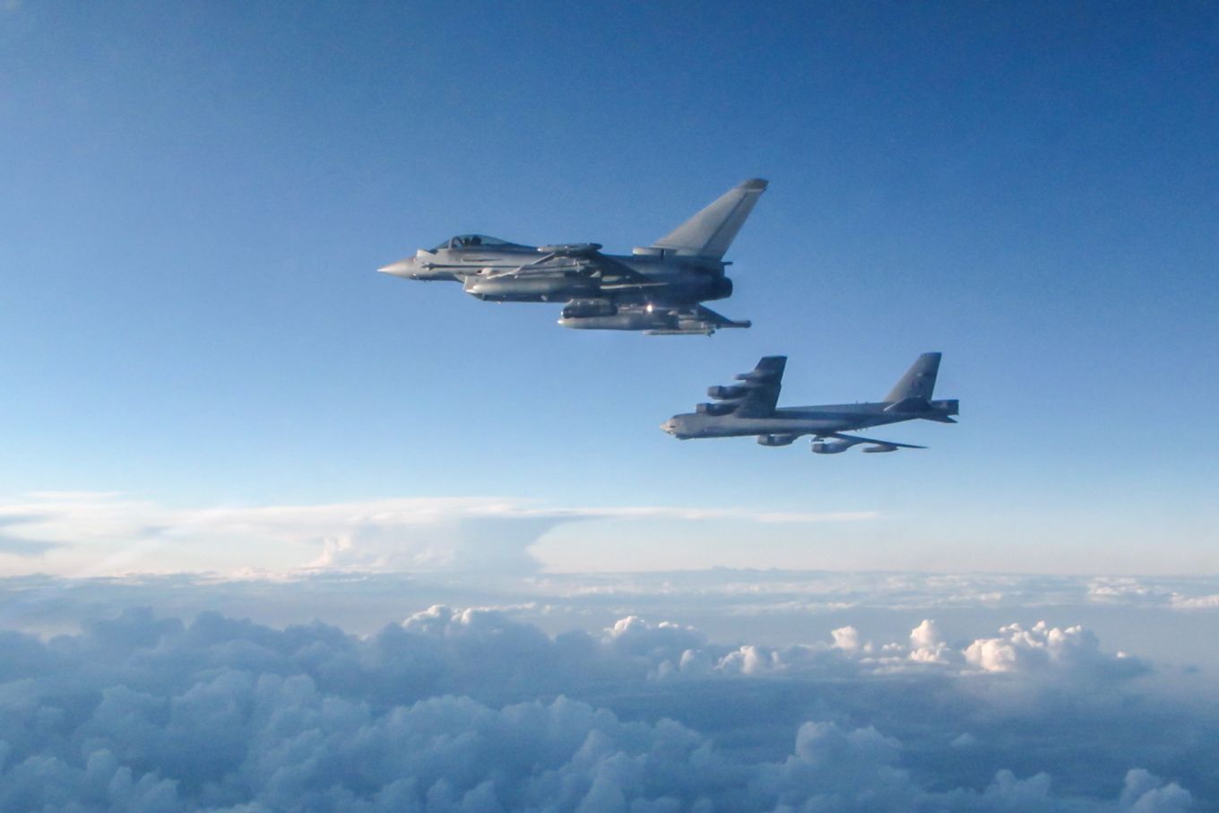 Typhoon and USAF B-52H Stratofortress long range bomber flying above the clouds.