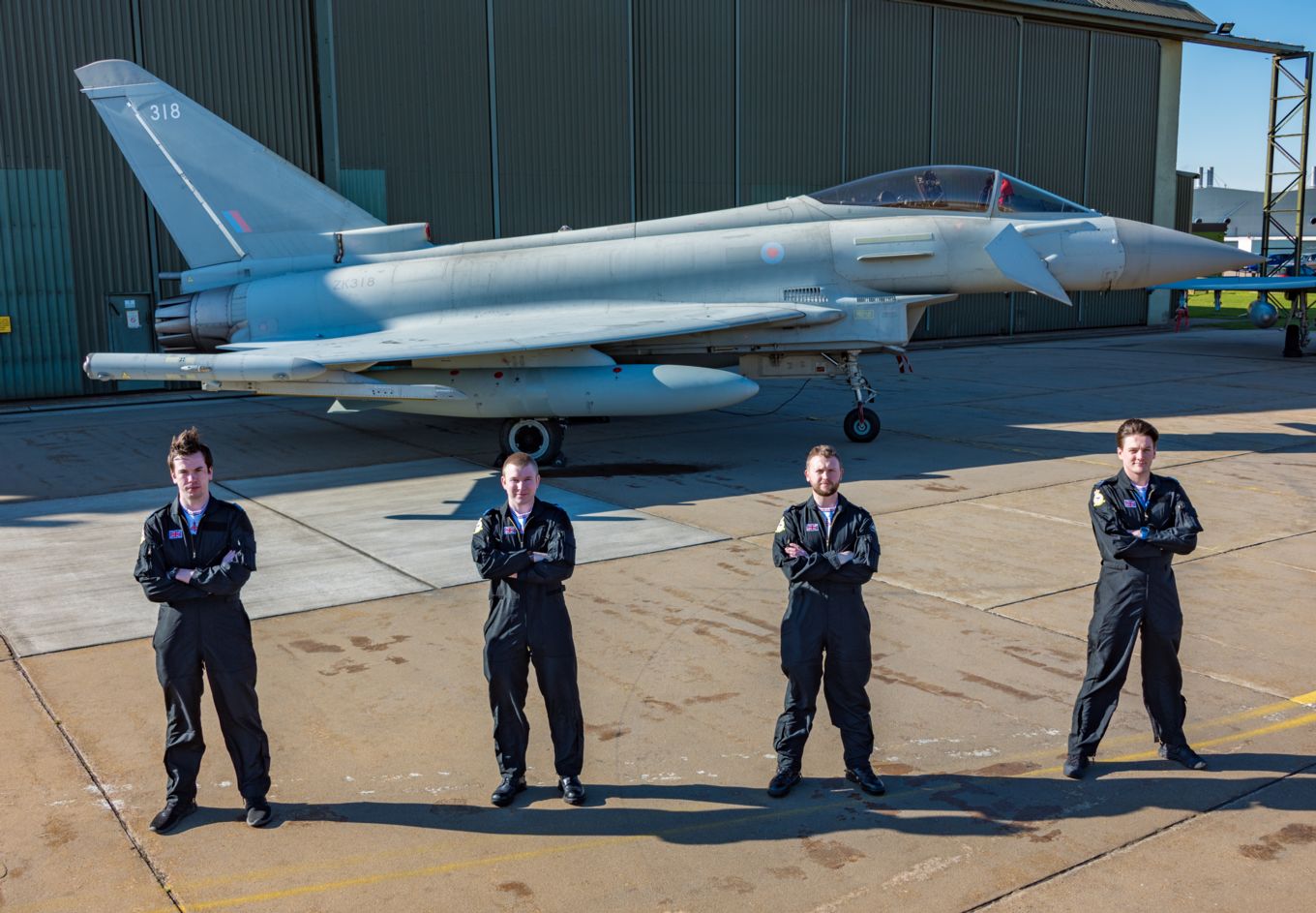 Team of personnel stand in formation with a Typhoon on the airfield.