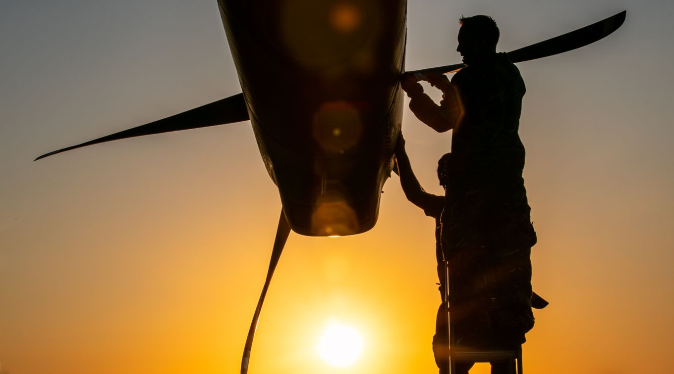 Maintenance of aircraft propellers and personnel with sunset.