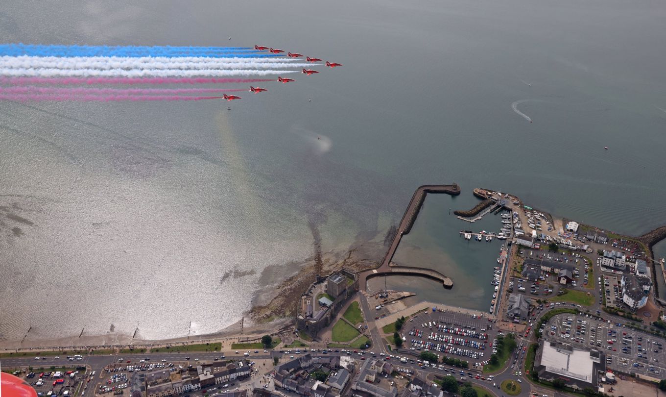 Image shows the RAF Red Arrows performing a flypast over Carrickfergus in Northern Ireland.