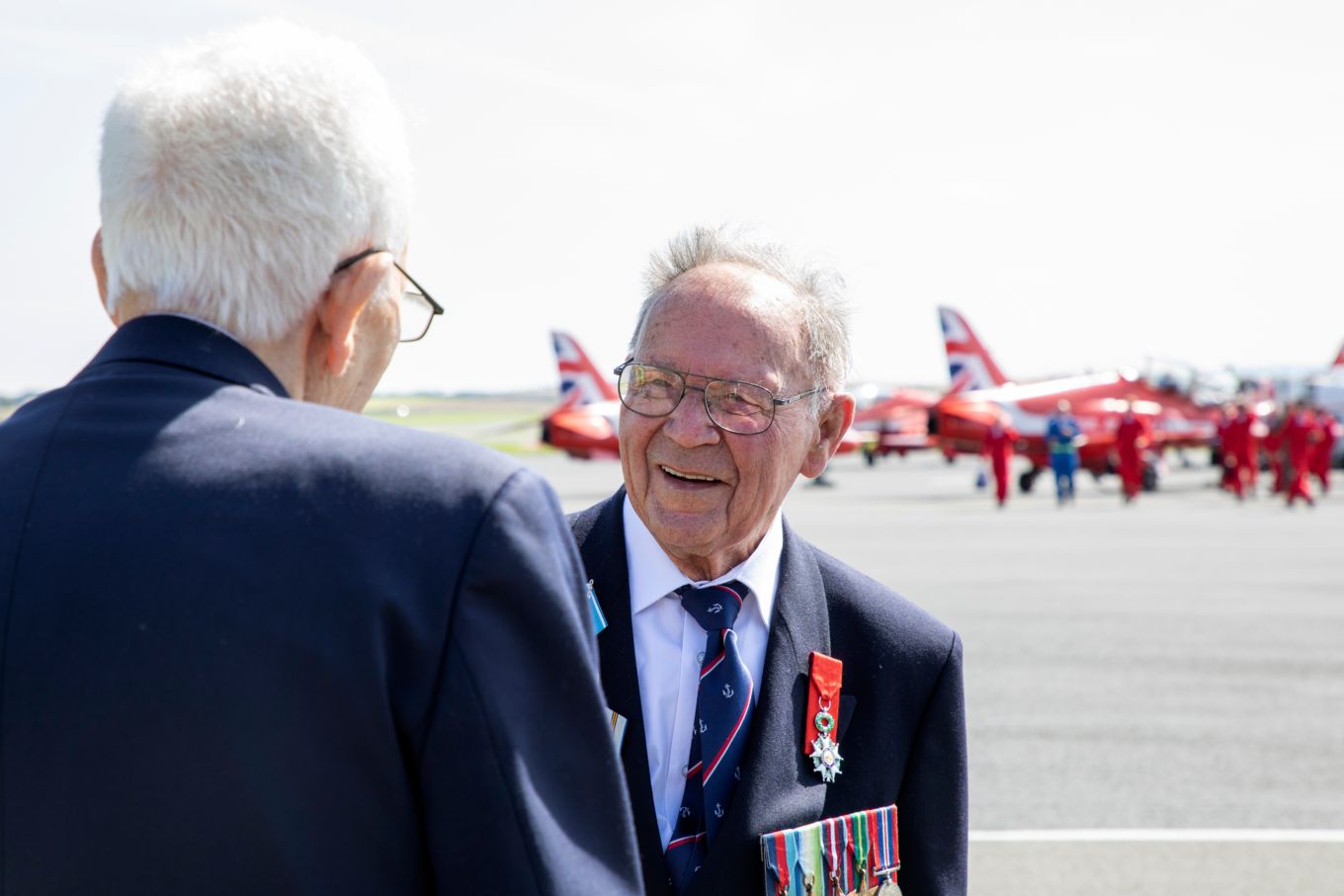 Image shows veterans next to Red Arrows aircraft.