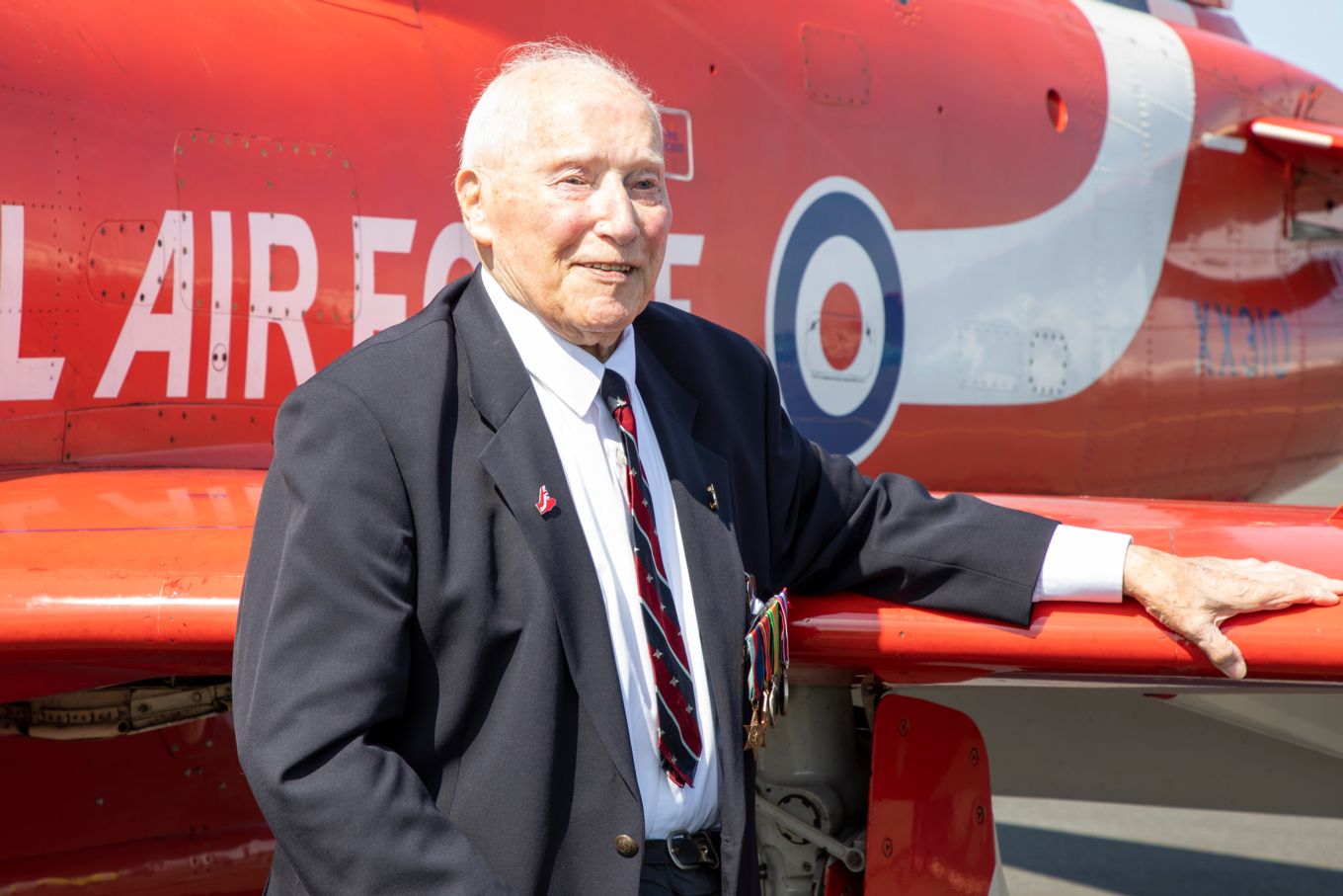 Image shows a veteran in front of a Red Arrow aircraft.