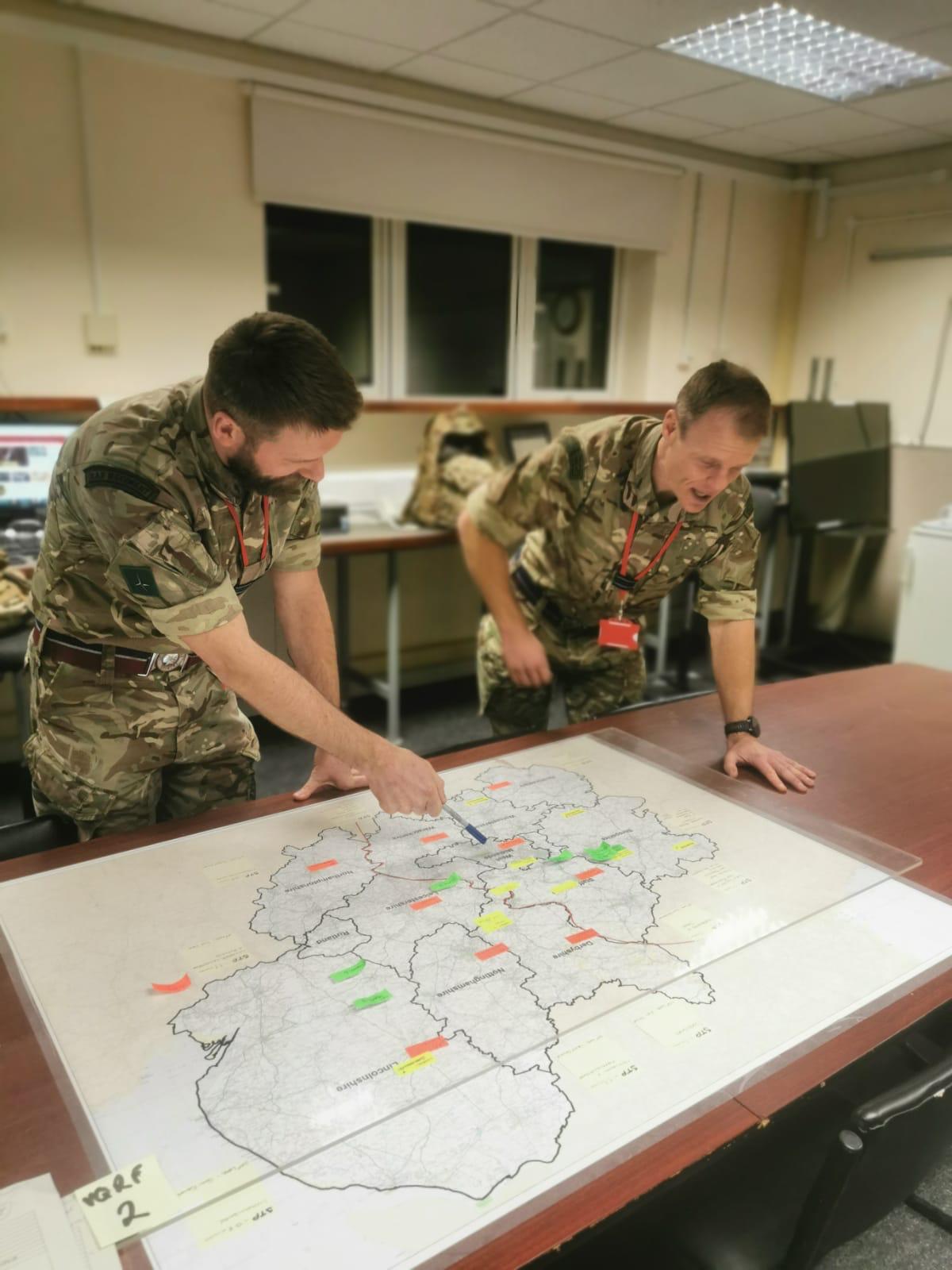Image shows Flight Lieutenants Clarke and Coatsworth working over a map on a table.
