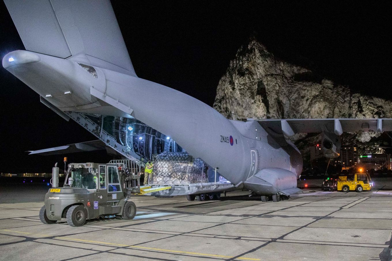 Boeing C-17 Globemaster with cargo being unloaded and transport vehicles. 