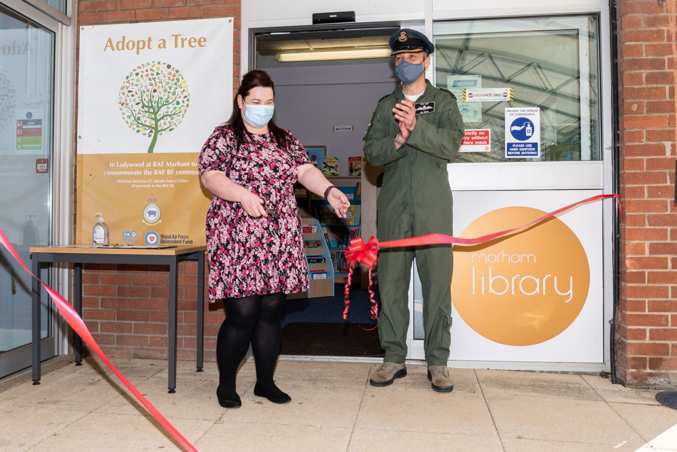 Female staff member cuts the ribbon, officially opening the library, Station Commander stood alongside clapping