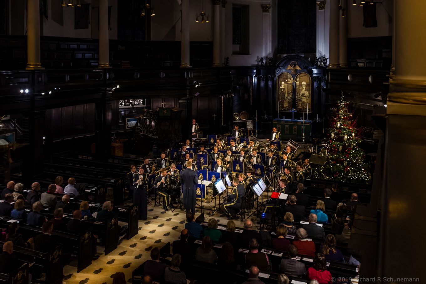 A military band perform a concert in a packed church.