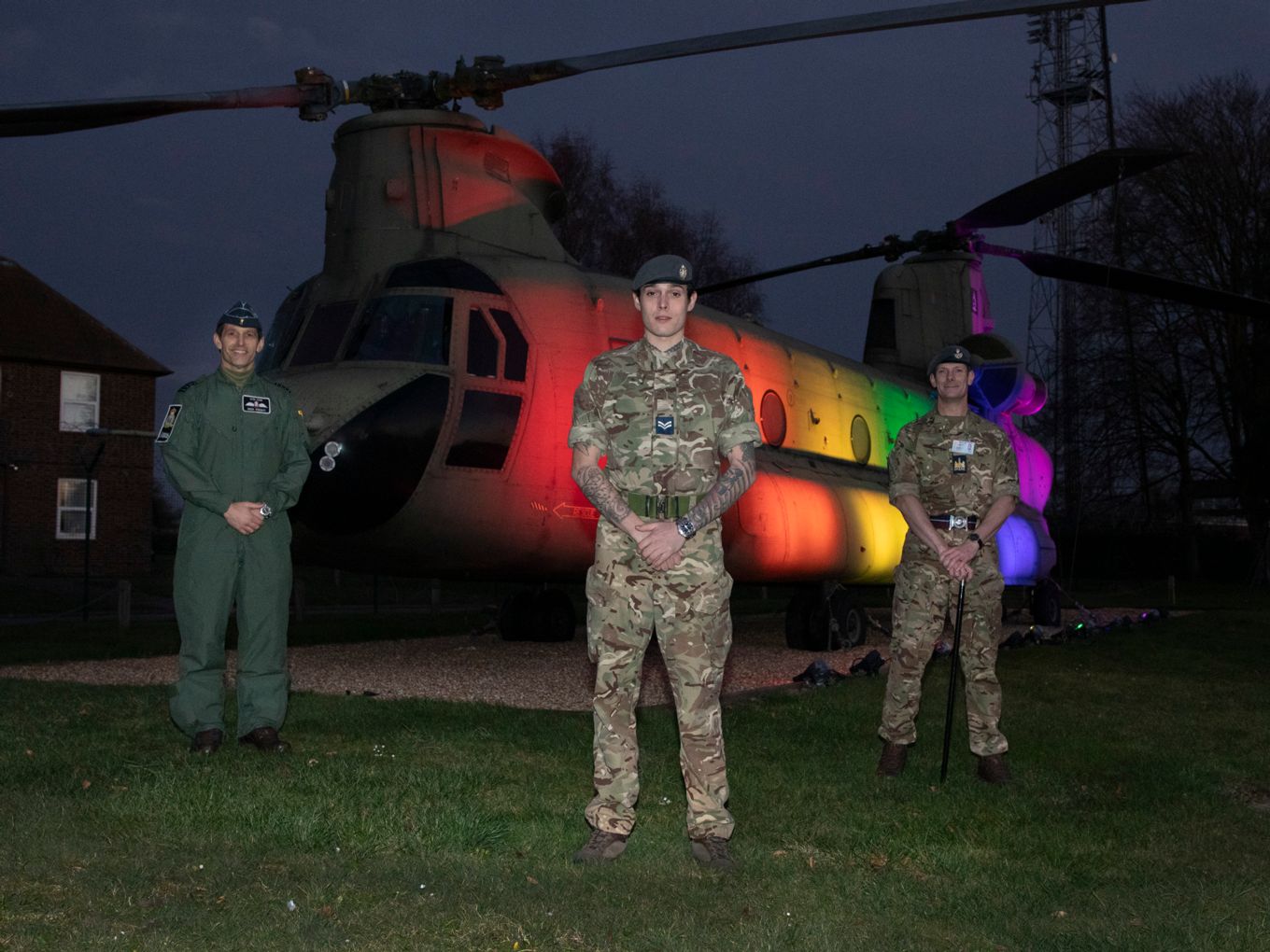 RAF Odiham Chinook Gate Guardian illuminated in Pride colours to support LGBT+ History Month 2021. Pictured: Station Commander (left), Corporal Farren Ekins (centre), Station Warrant Officer (right). 