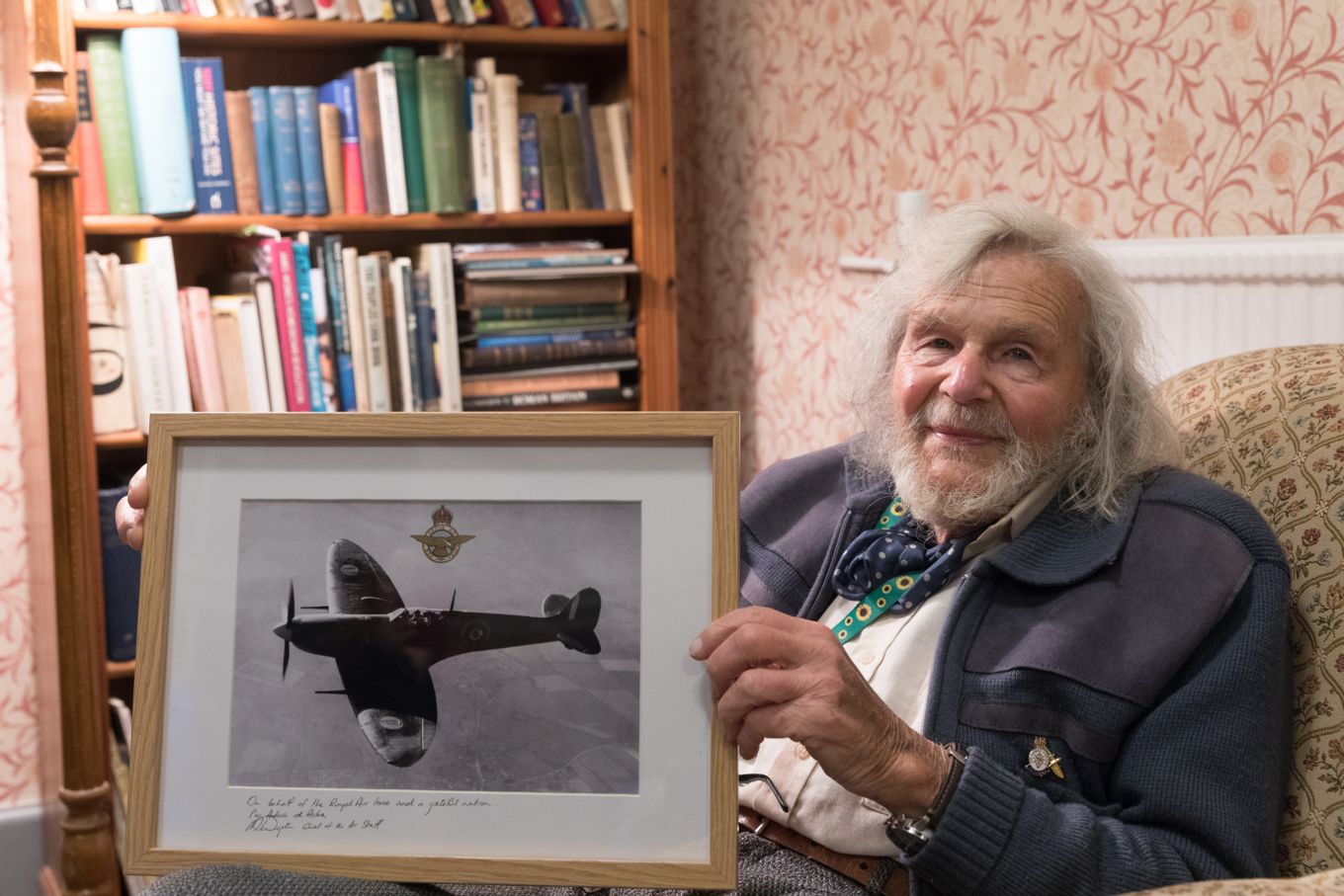 Image shows Dr Edmund James holding his new black and white photo of him flying a Spitfire.