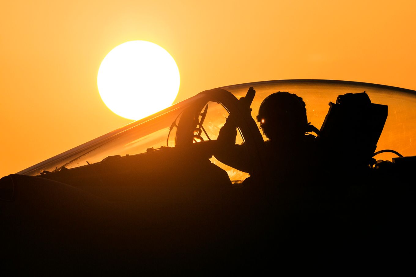 Pilot waves from aircraft with sunset background. 
