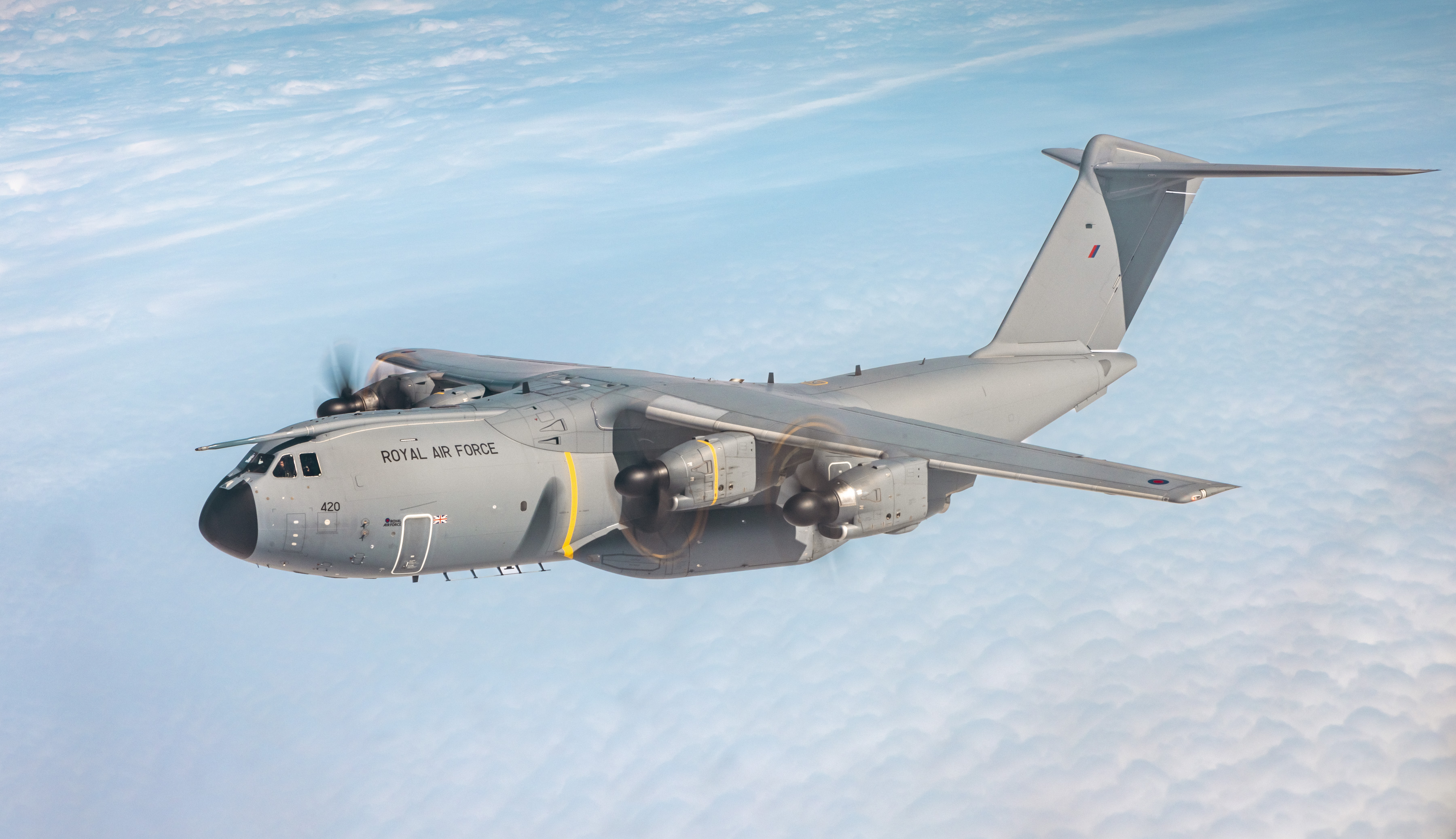 A400M flying against backdrop of bright blue skies and wispy clouds