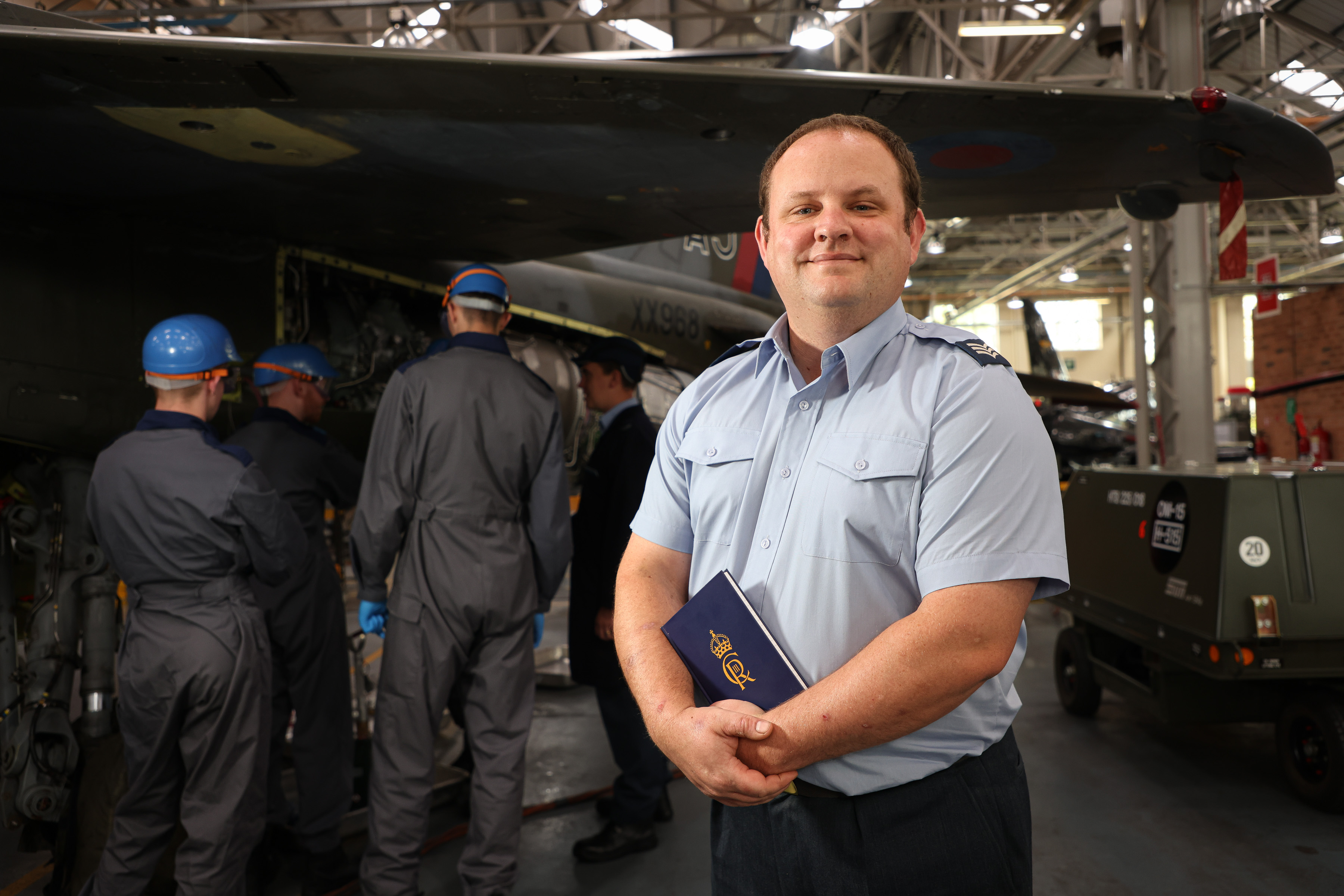 Sgt Chris Adamson stood in front of apprentices undertaking a practical lesson under a Jaguar within Mechanical Training Squadron. 