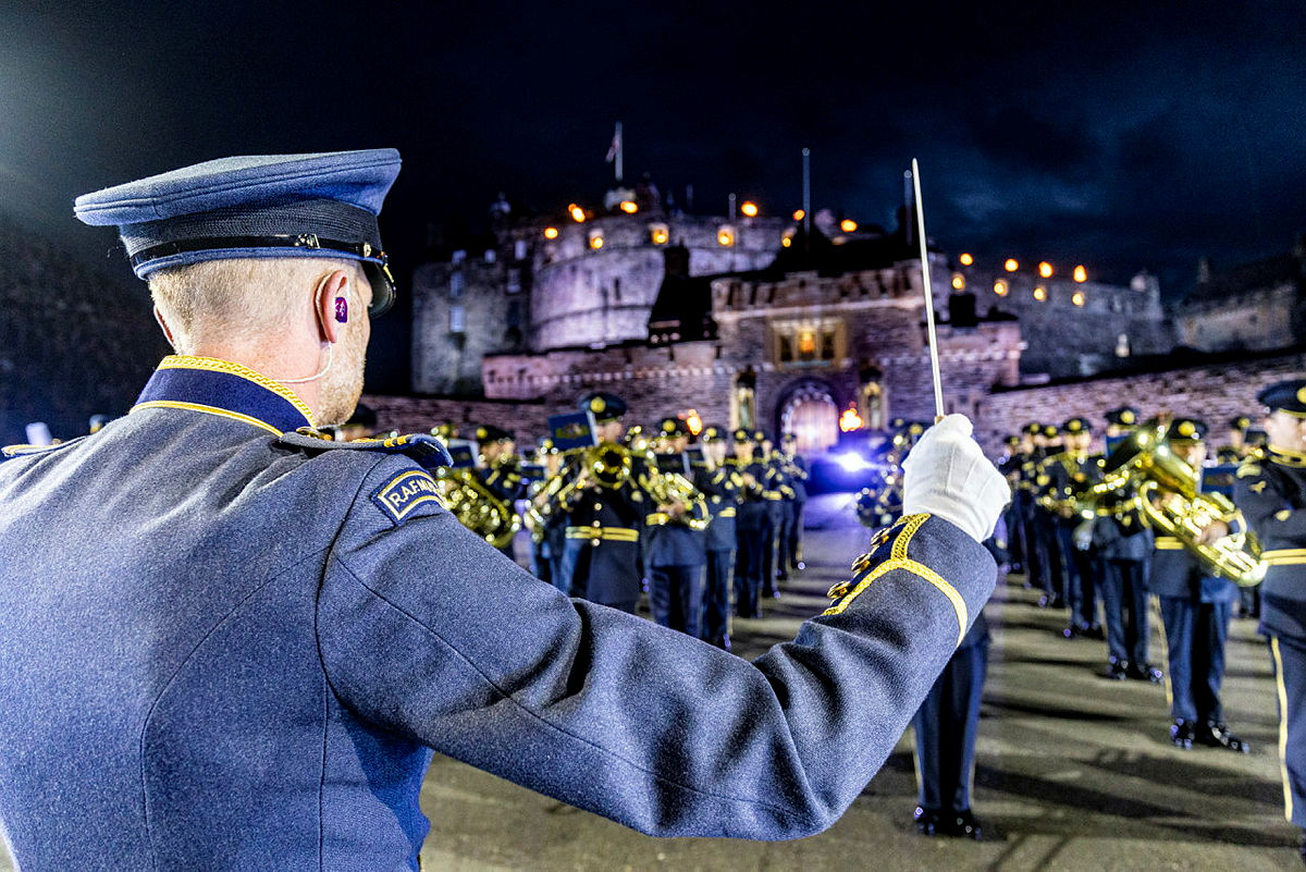RAF band performing outside Edinburgh Castle at night with conductor in the foreground