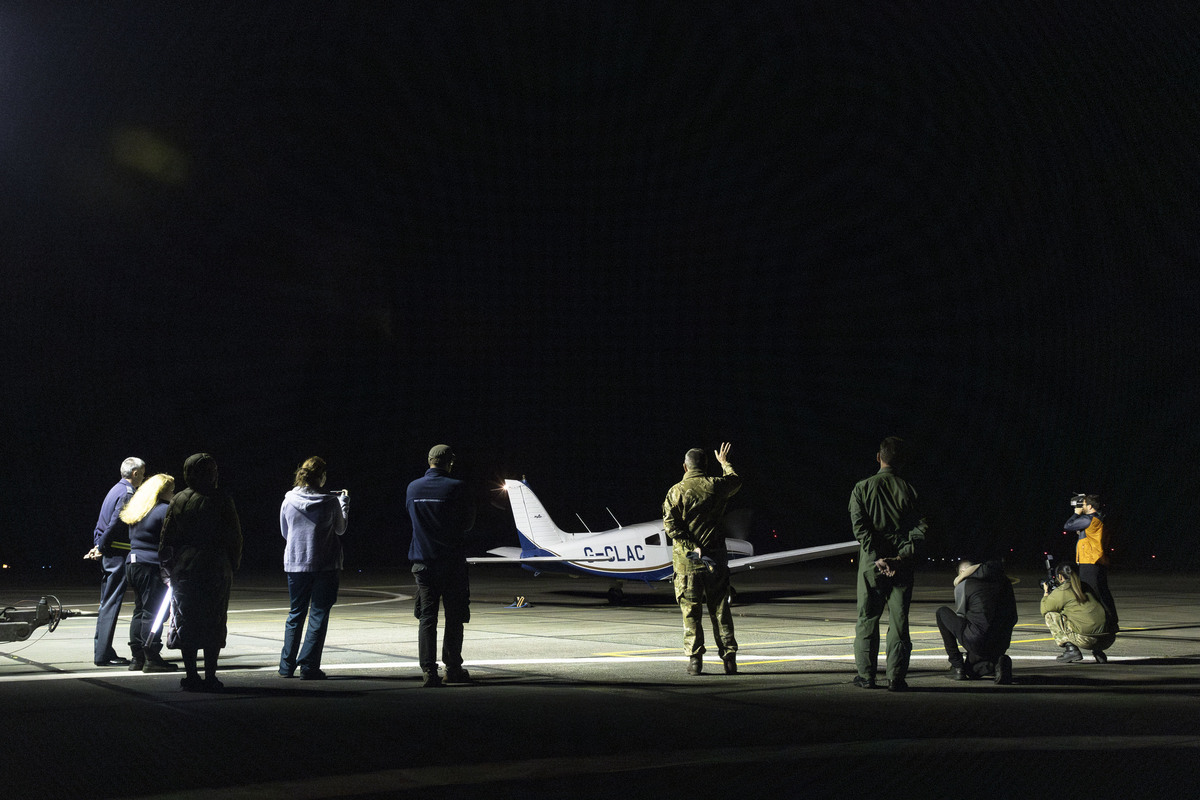 people on runway at night waving off the light aircraft carrying Tally the turtle to RAF Northolt